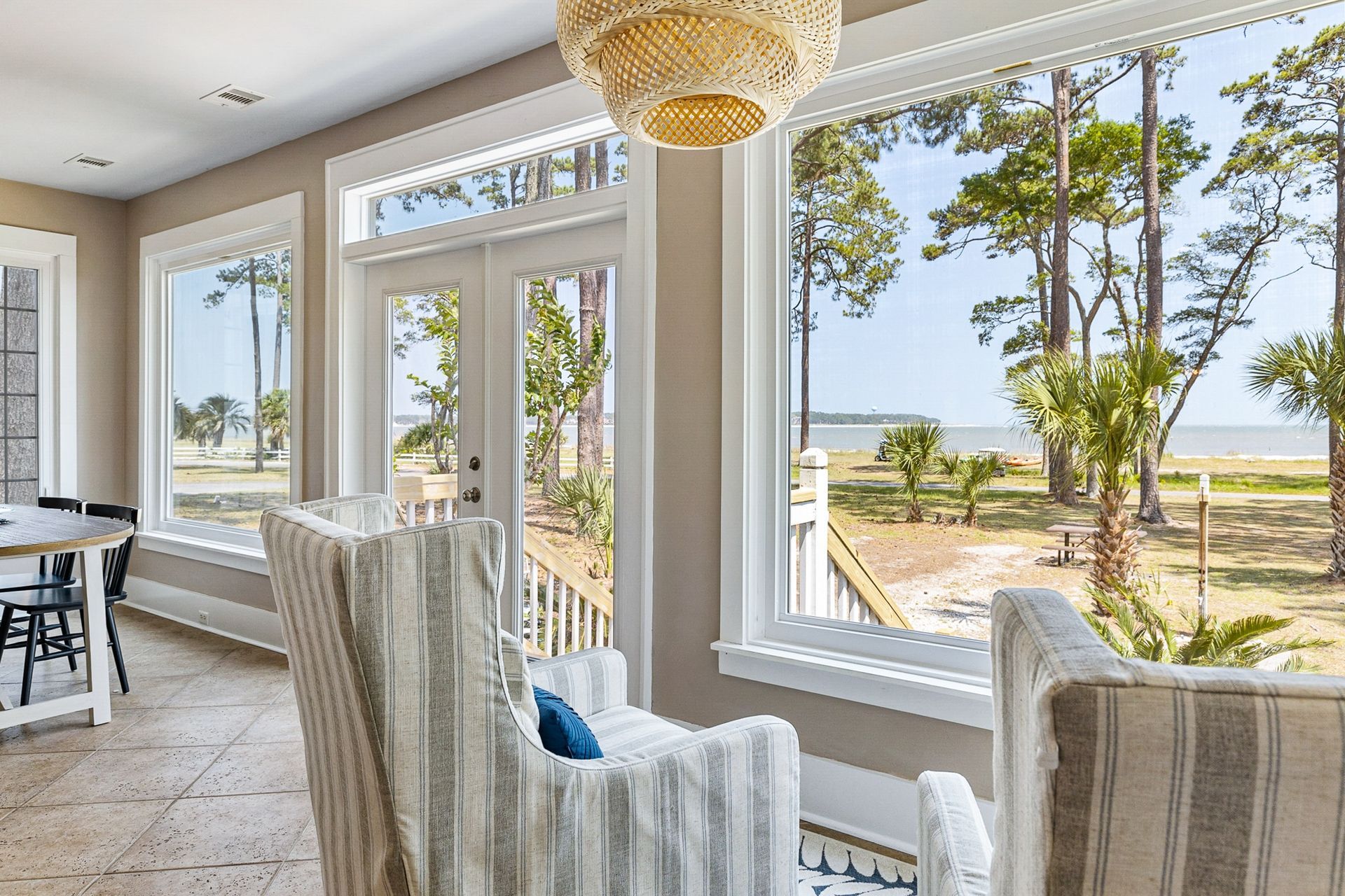 A living room with two chairs and a table with a view of the ocean.