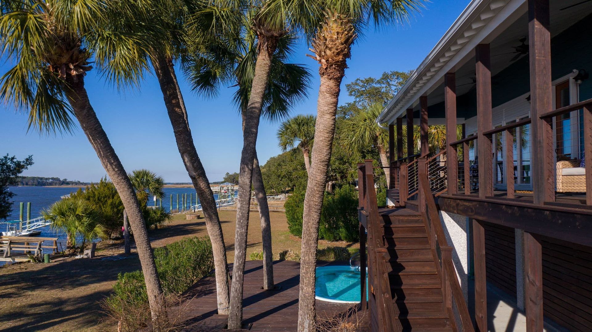 A house with a swimming pool and palm trees in front of it.