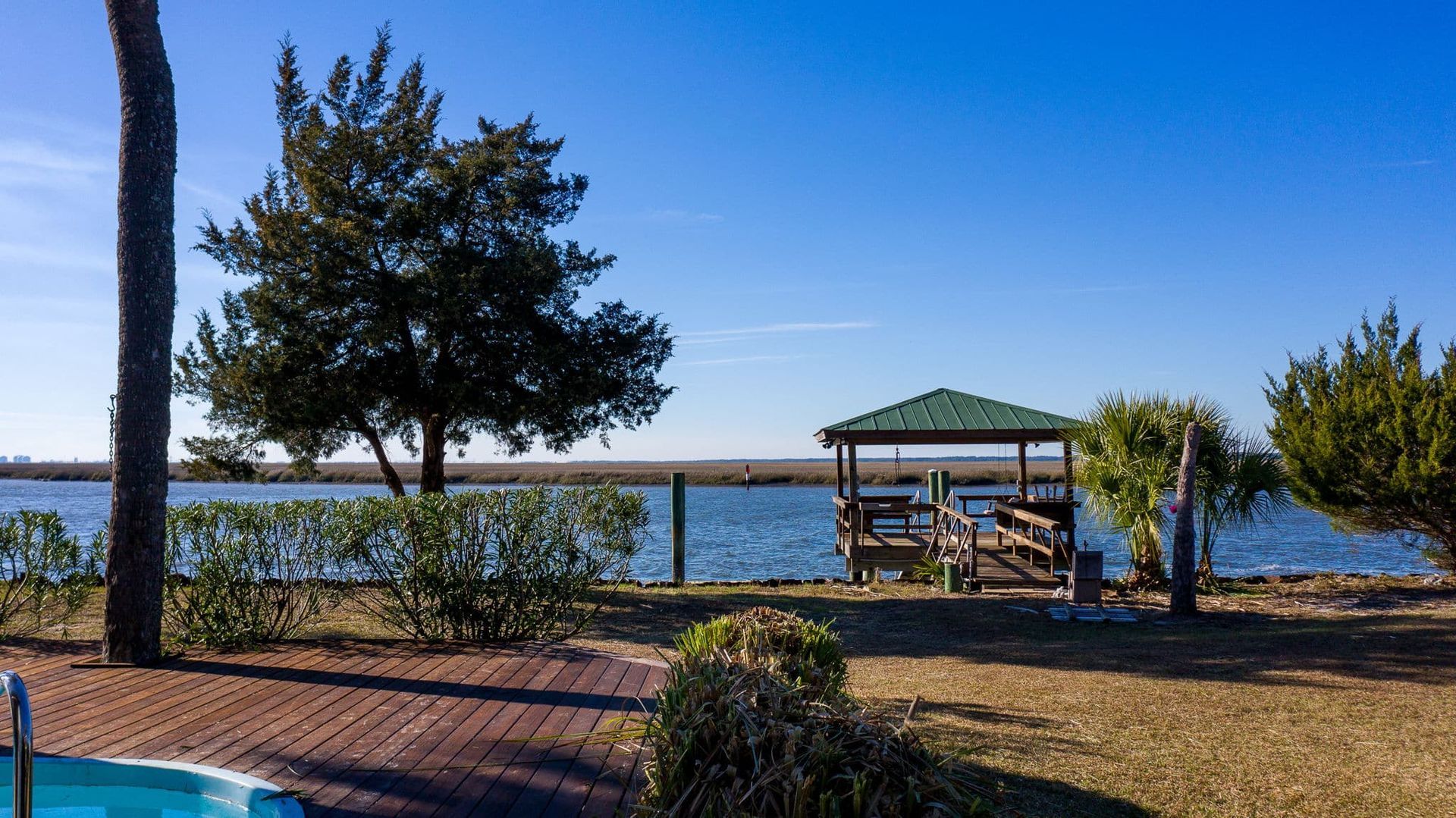 A swimming pool with a gazebo in the background next to a body of water.