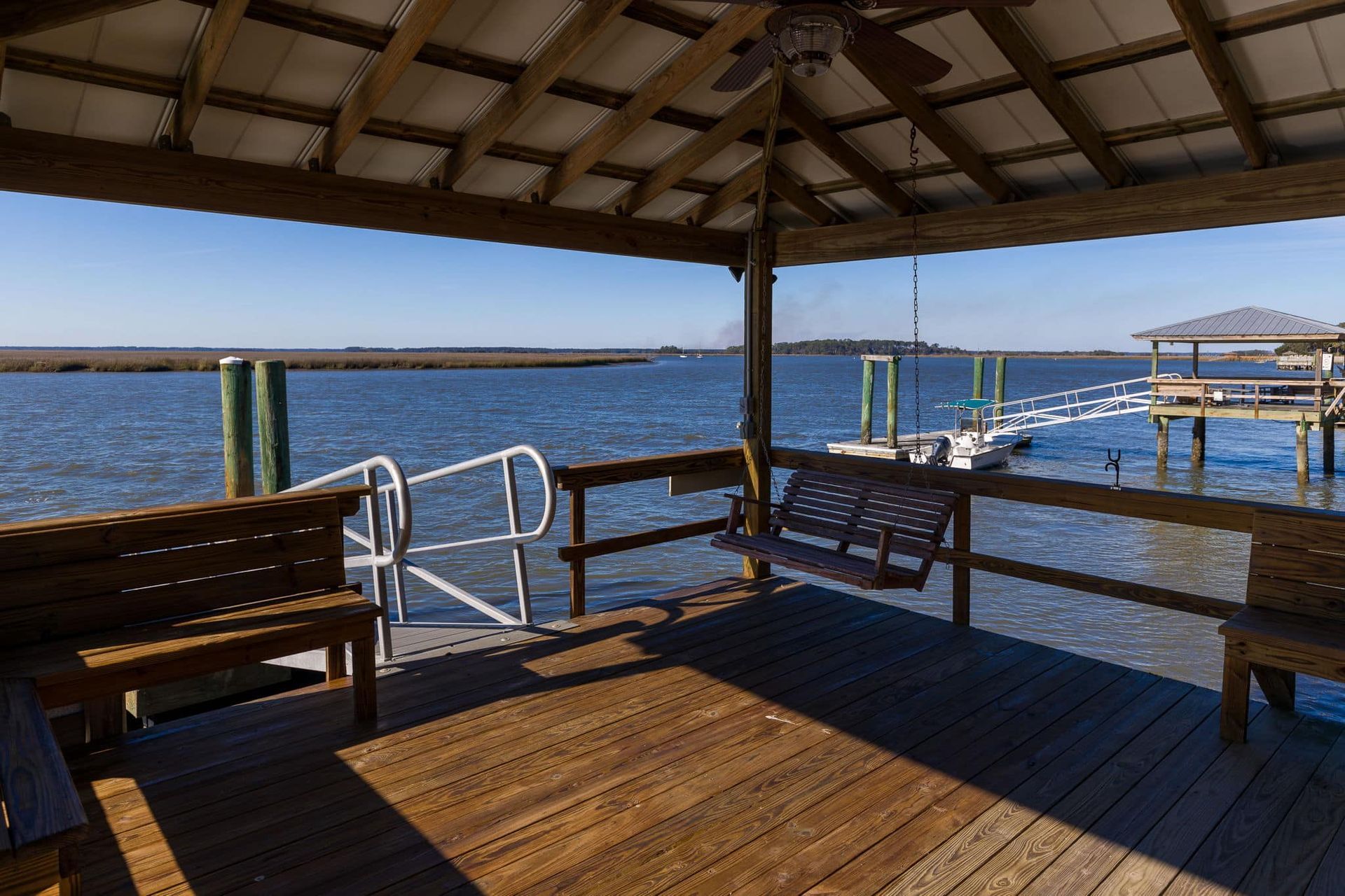 A wooden deck overlooking a body of water with a ceiling fan.