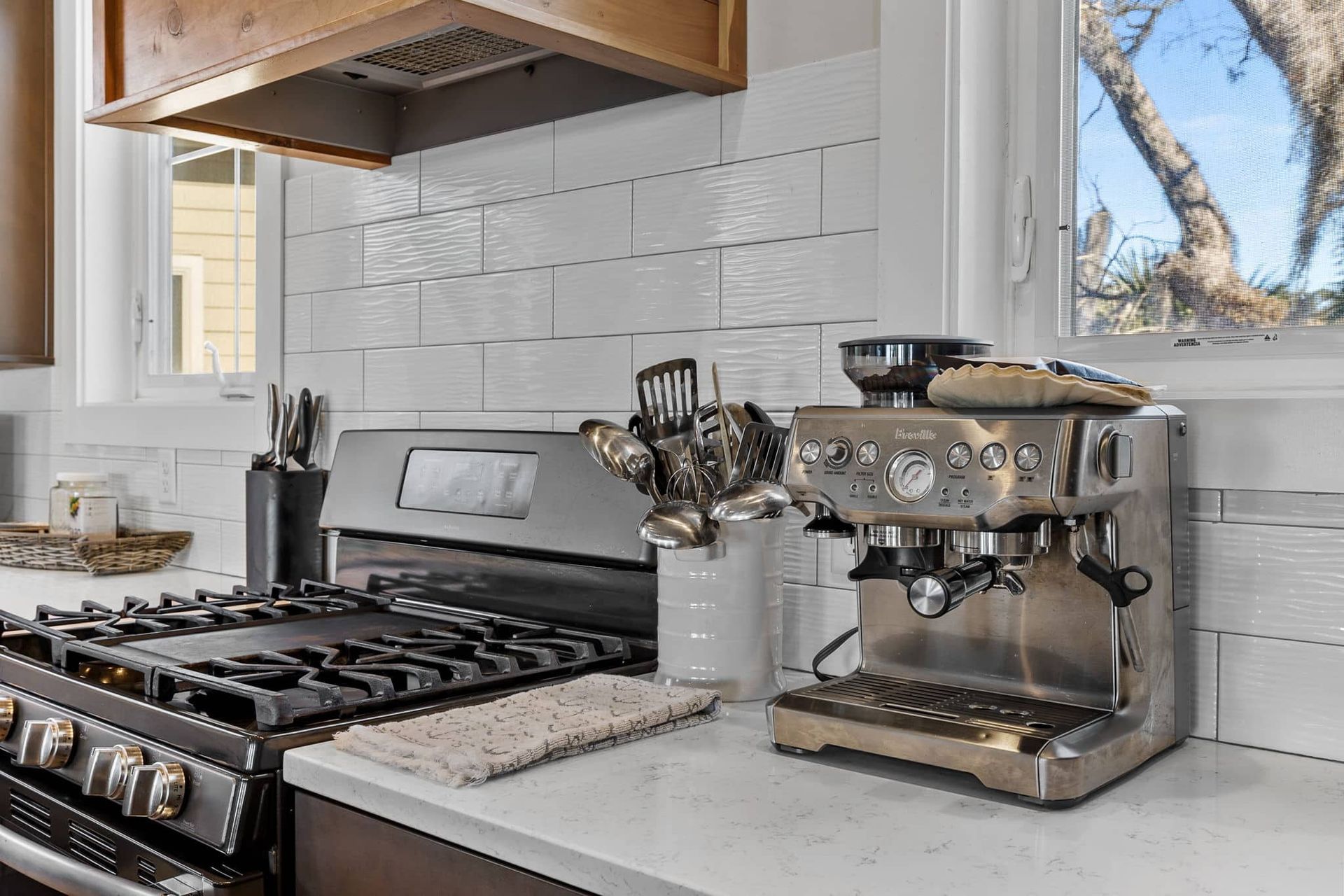 A kitchen with a stove and a coffee maker on the counter.