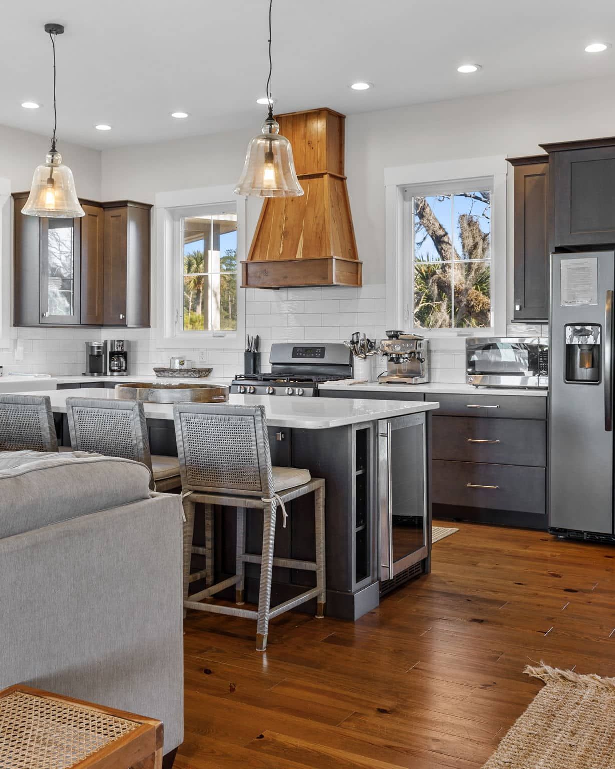A kitchen with a stainless steel refrigerator , stove , sink , and wooden floors.