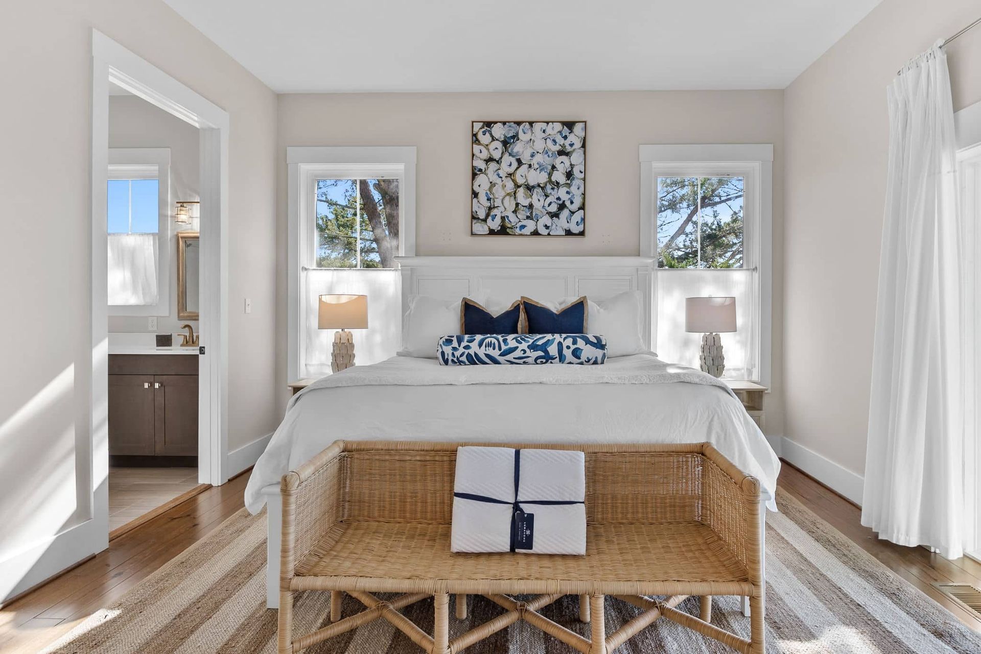A bedroom with a bed , bench , lamps , and a painting on the wall.