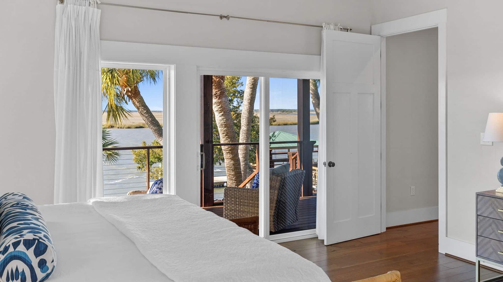 A bedroom with a large bed and a balcony overlooking the water.