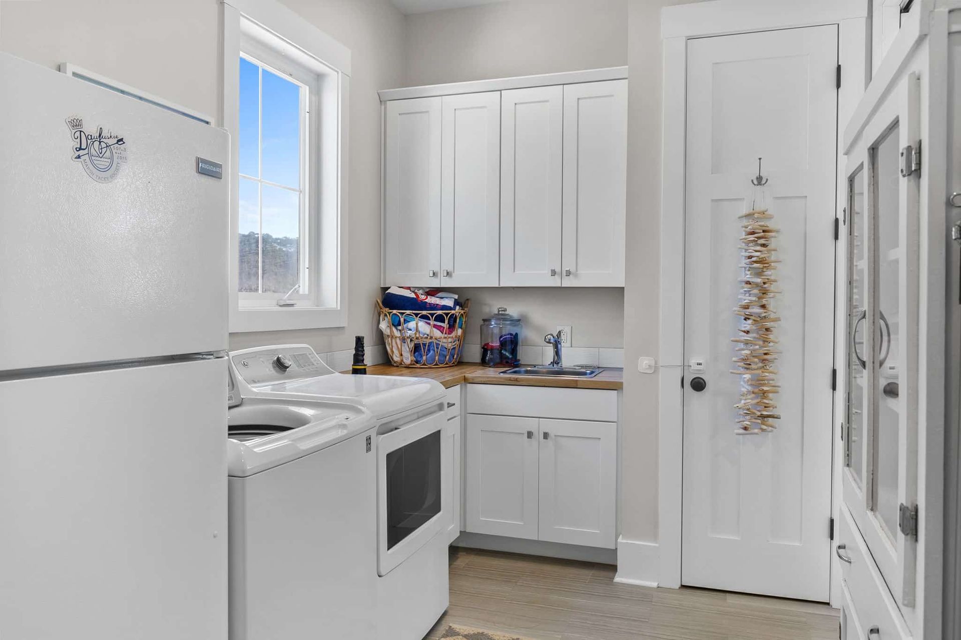 A laundry room with a refrigerator , washer and dryer , and a window.
