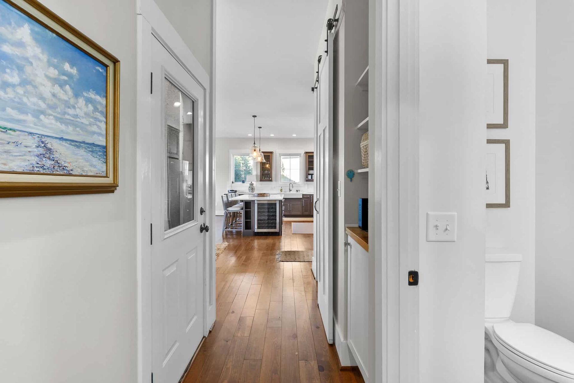 A hallway in a house with a toilet and a painting on the wall.