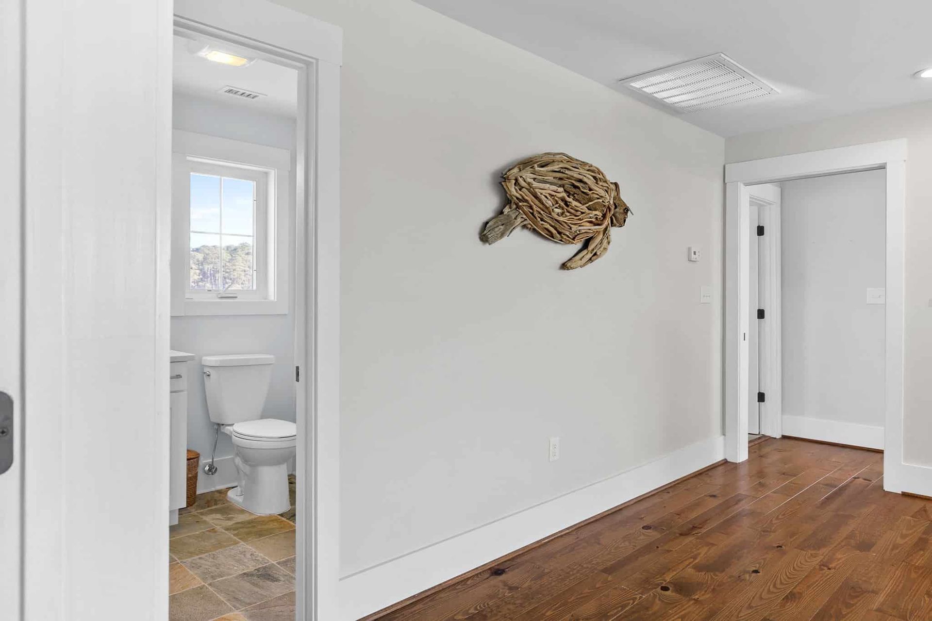 A hallway with a toilet and a turtle on the wall.