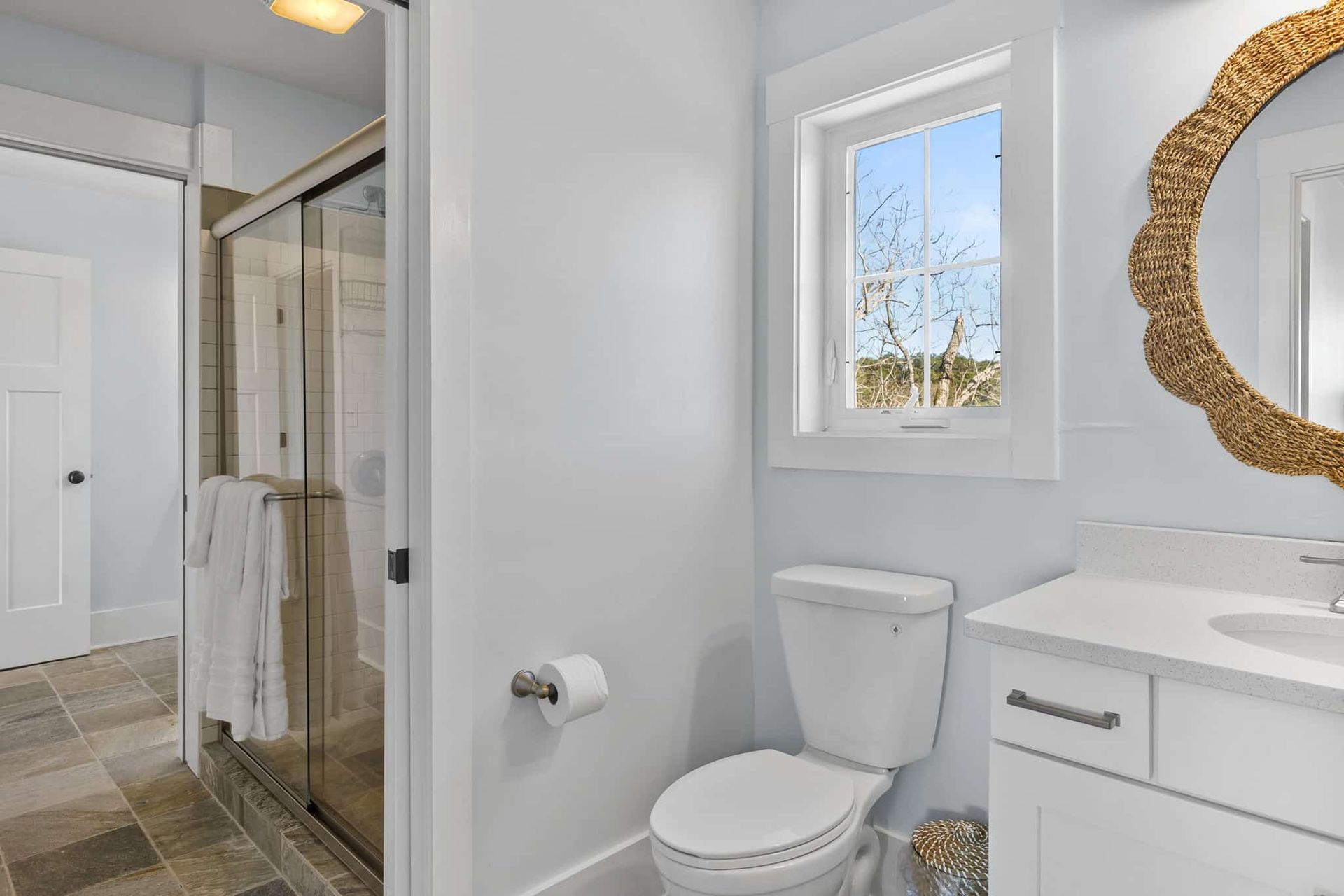 A bathroom with a toilet , sink , mirror and shower.