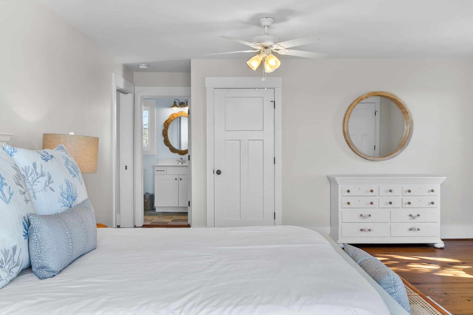 A bedroom with a bed , dresser , mirror and ceiling fan.