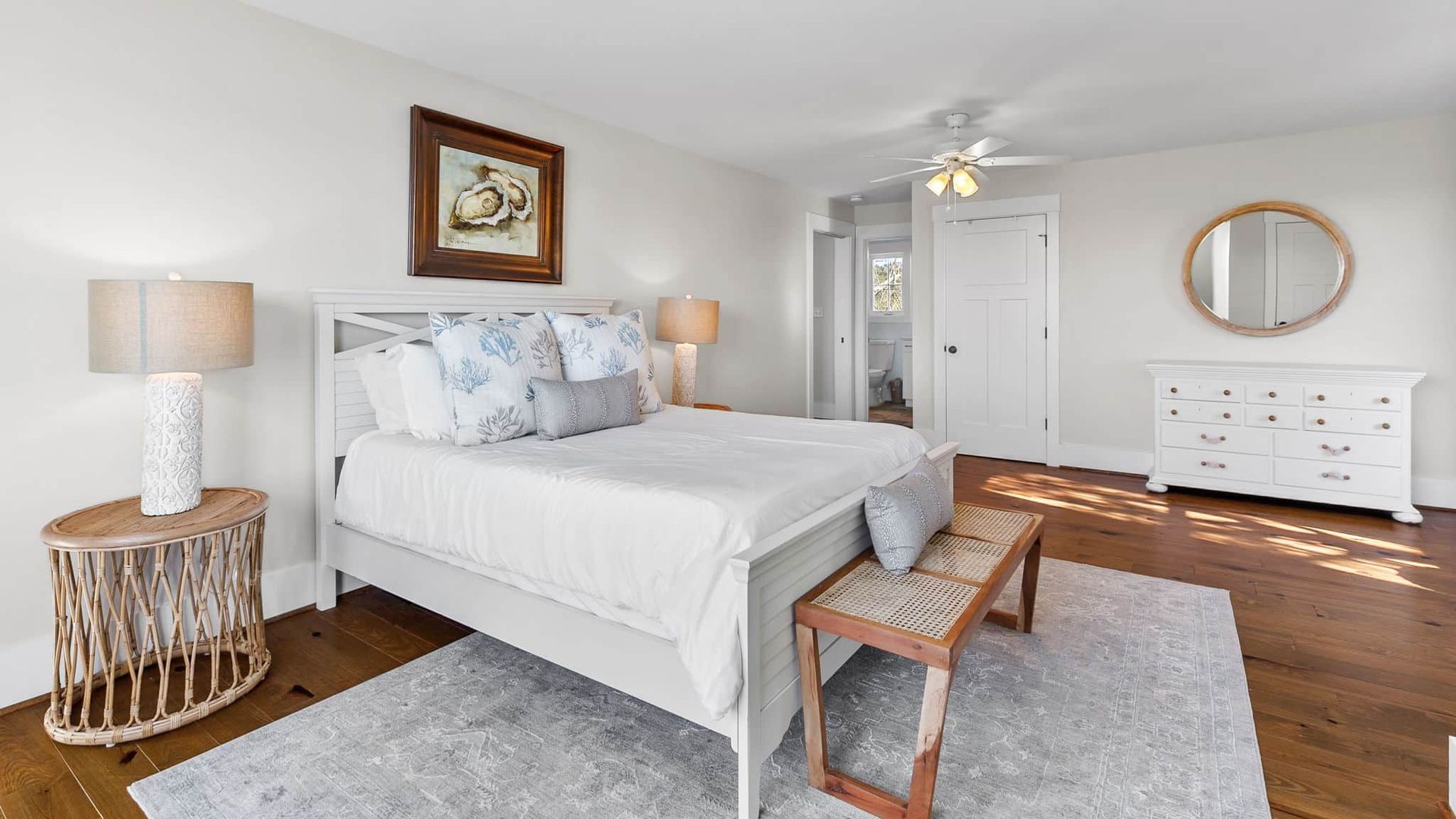 A bedroom with a bed , dresser , lamp , and mirror.