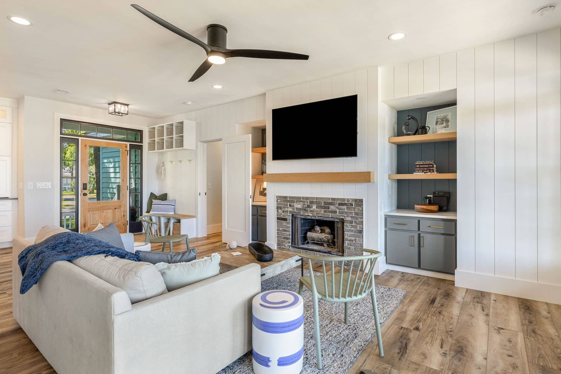 A living room with a couch , fireplace , television and ceiling fan.
