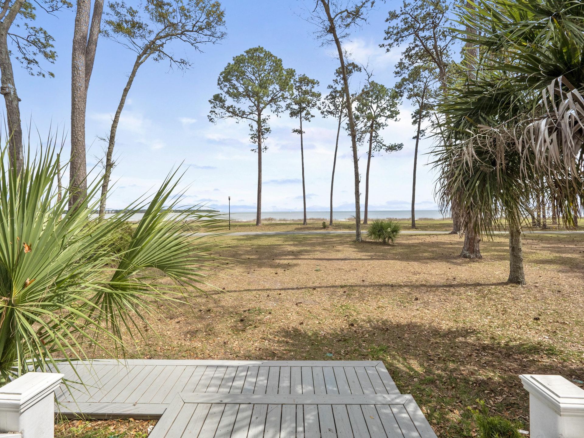 A view of the ocean from a deck with trees in the background.