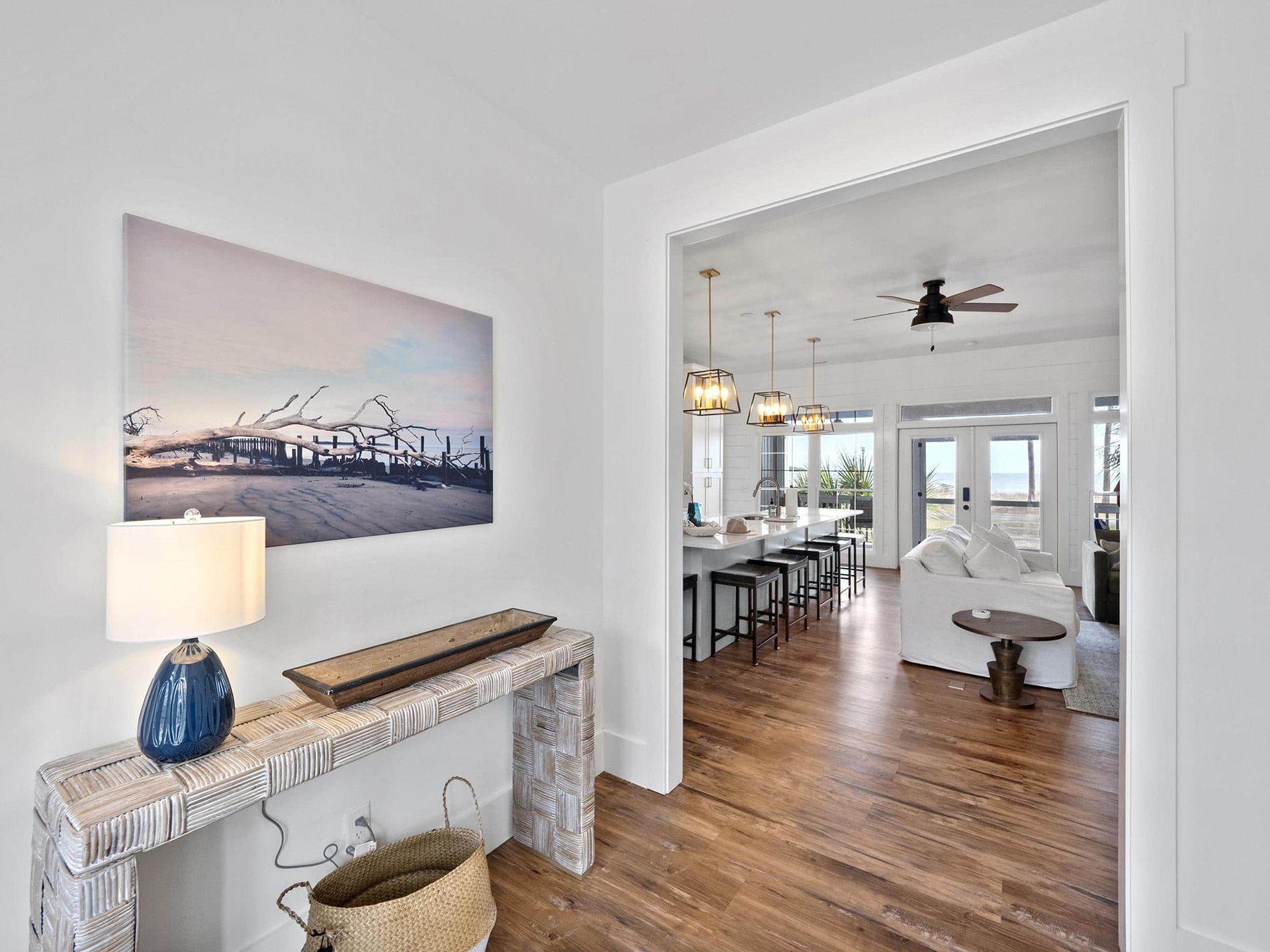A hallway leading to a living room with hardwood floors and a painting on the wall.