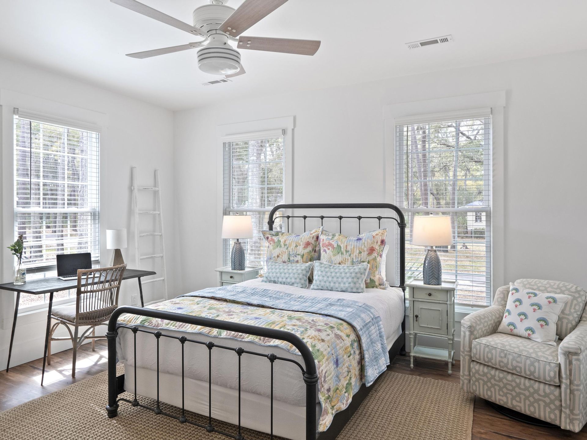 A bedroom with a bed , chair , desk and ceiling fan.