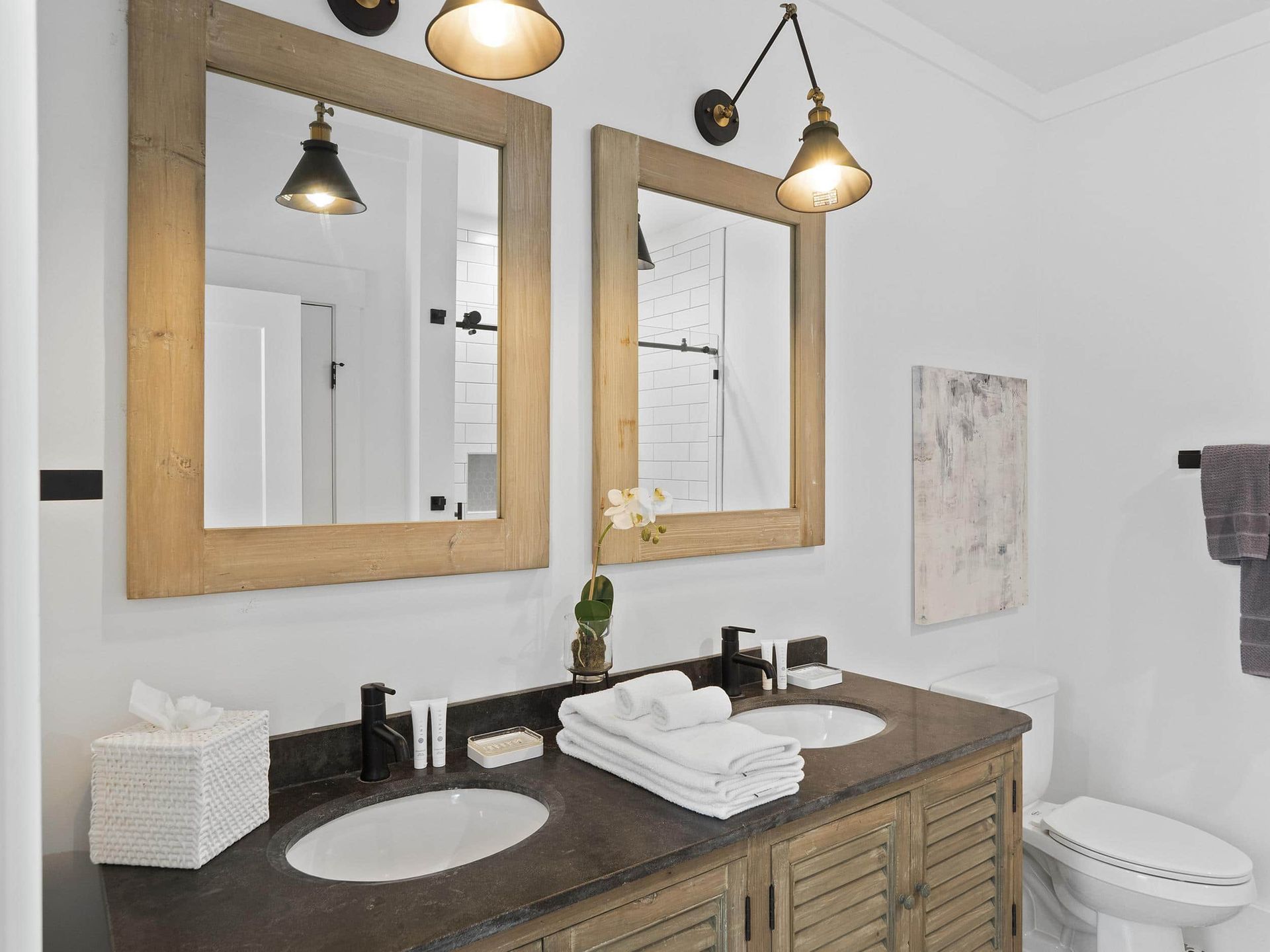 A bathroom with two sinks , a toilet , and two mirrors.
