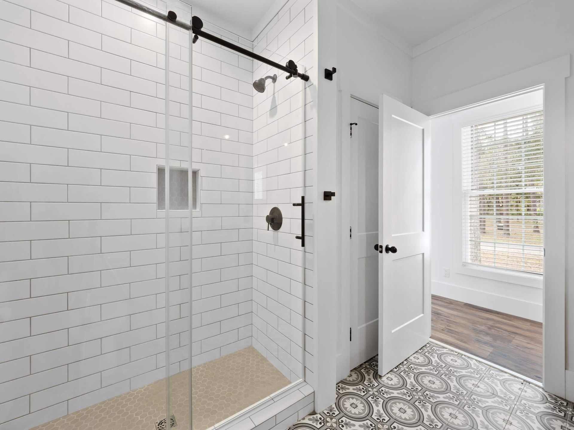 A bathroom with white tiles and a sliding glass shower door.