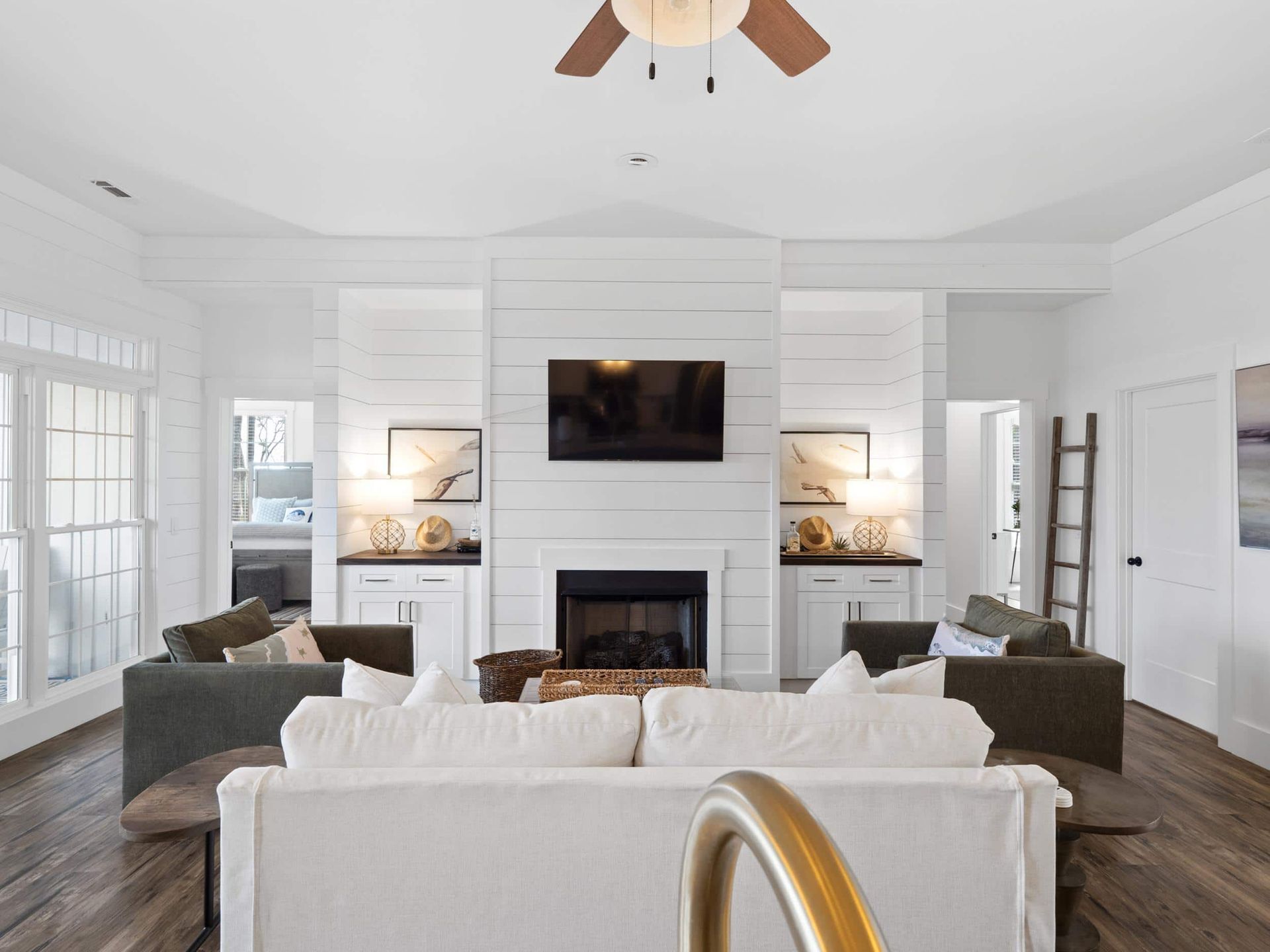 A living room with a couch , fireplace , television and ceiling fan.