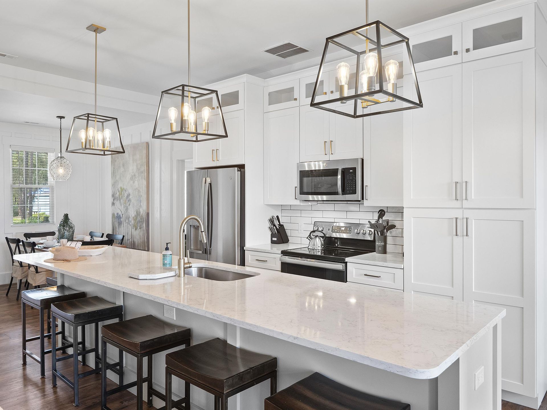 A kitchen with white cabinets , stainless steel appliances , and a large island.