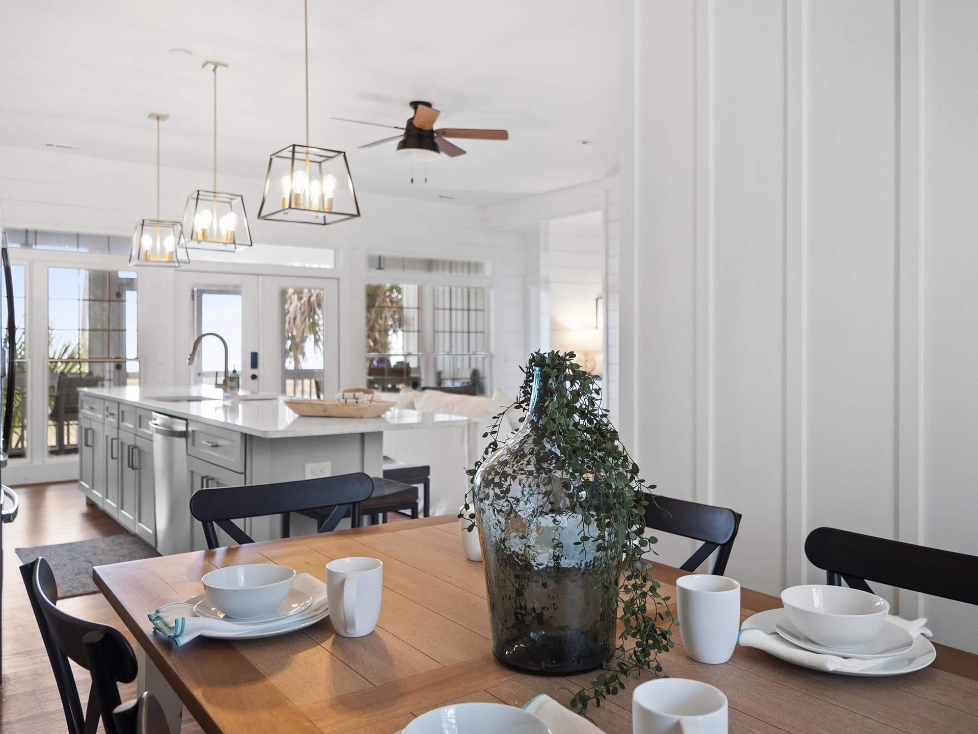 A dining room table with plates , bowls , and a vase on it.