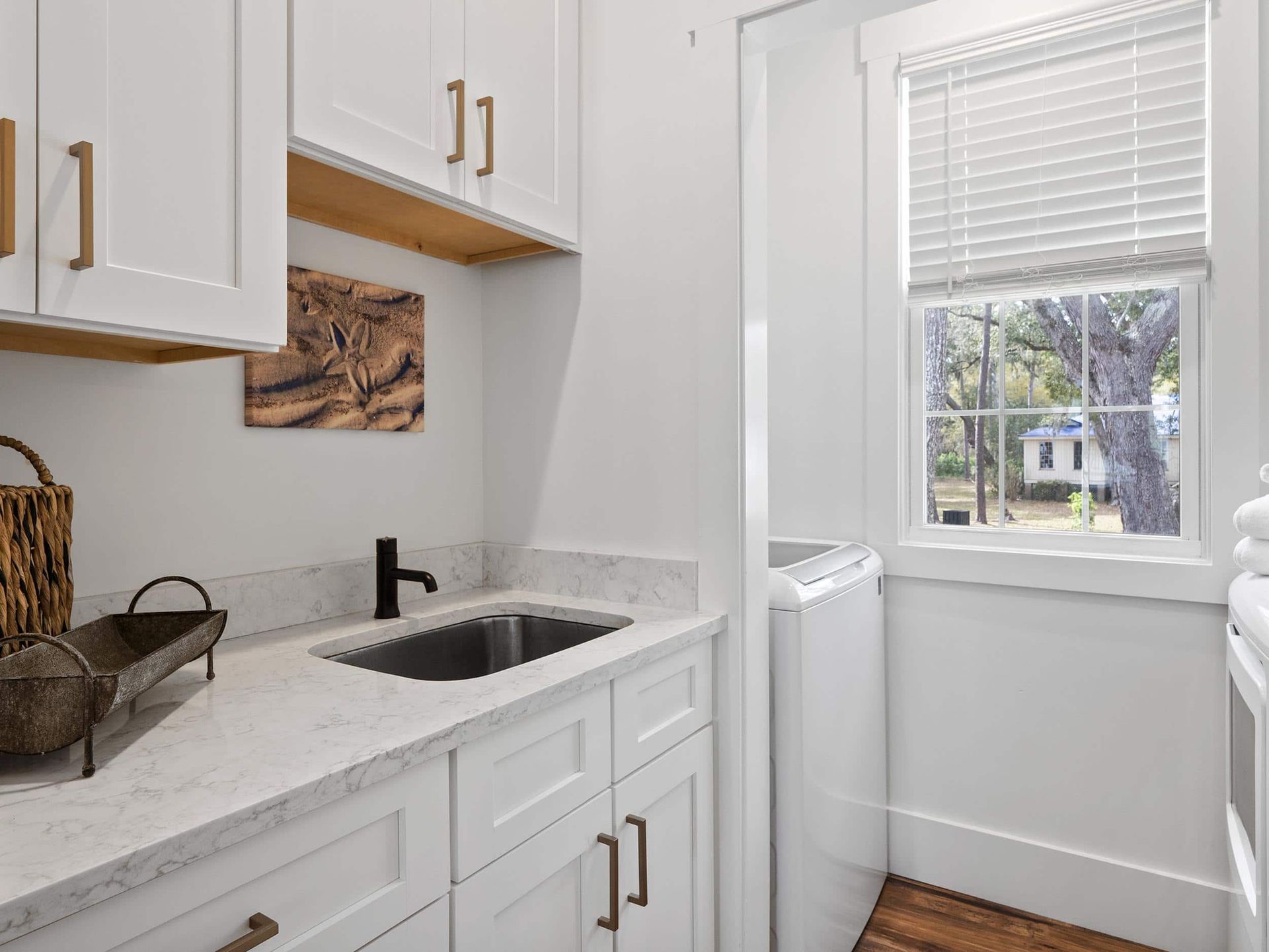 A laundry room with a sink , washer and dryer , and a window.