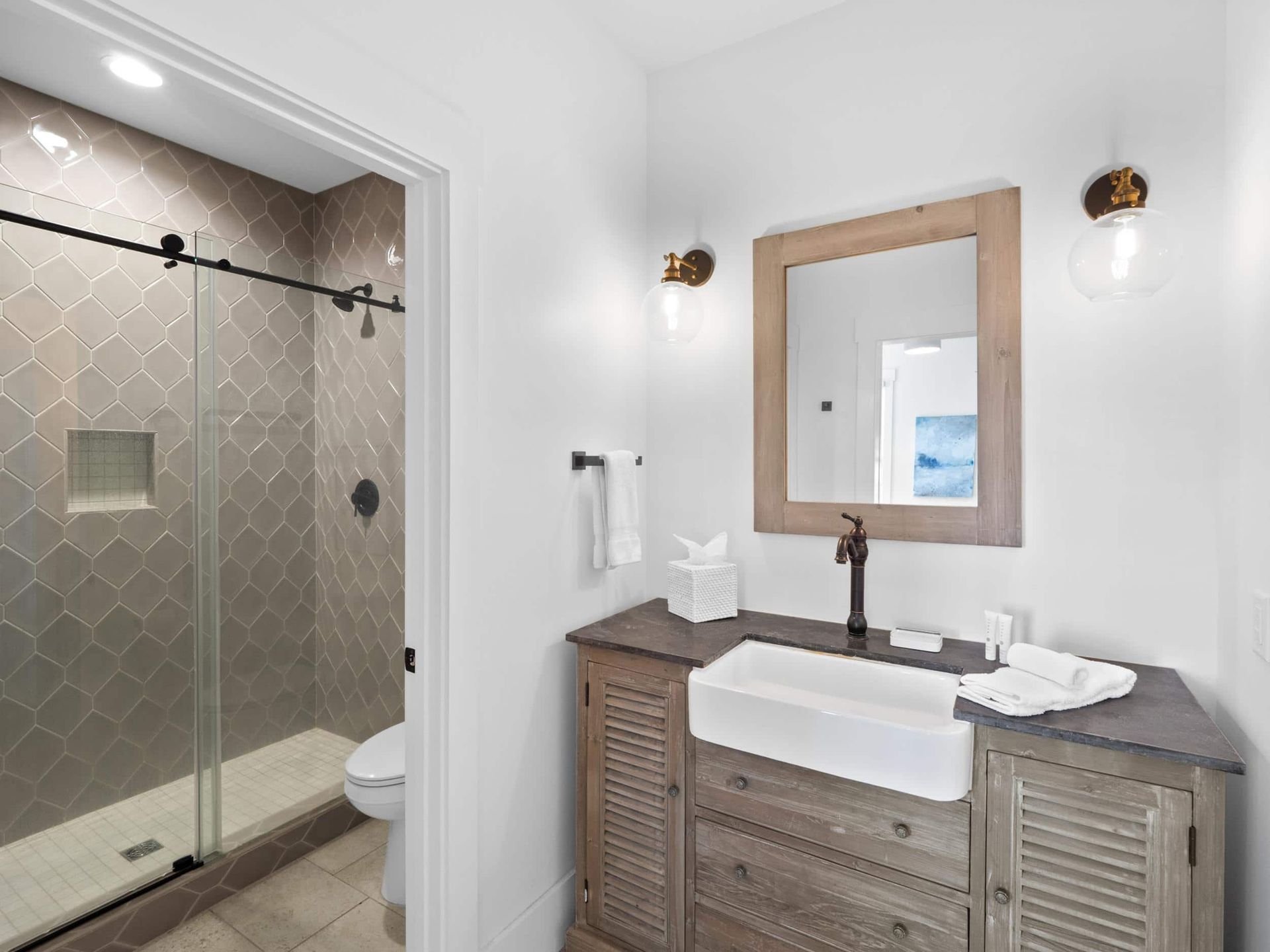 A bathroom with a sink , toilet , shower and mirror.