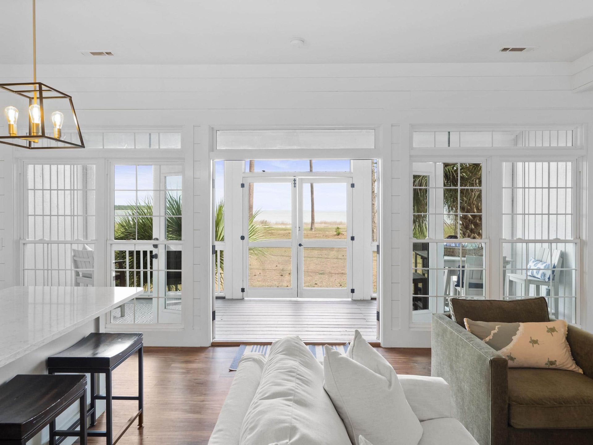 A living room with a couch , chair , table and lots of windows.