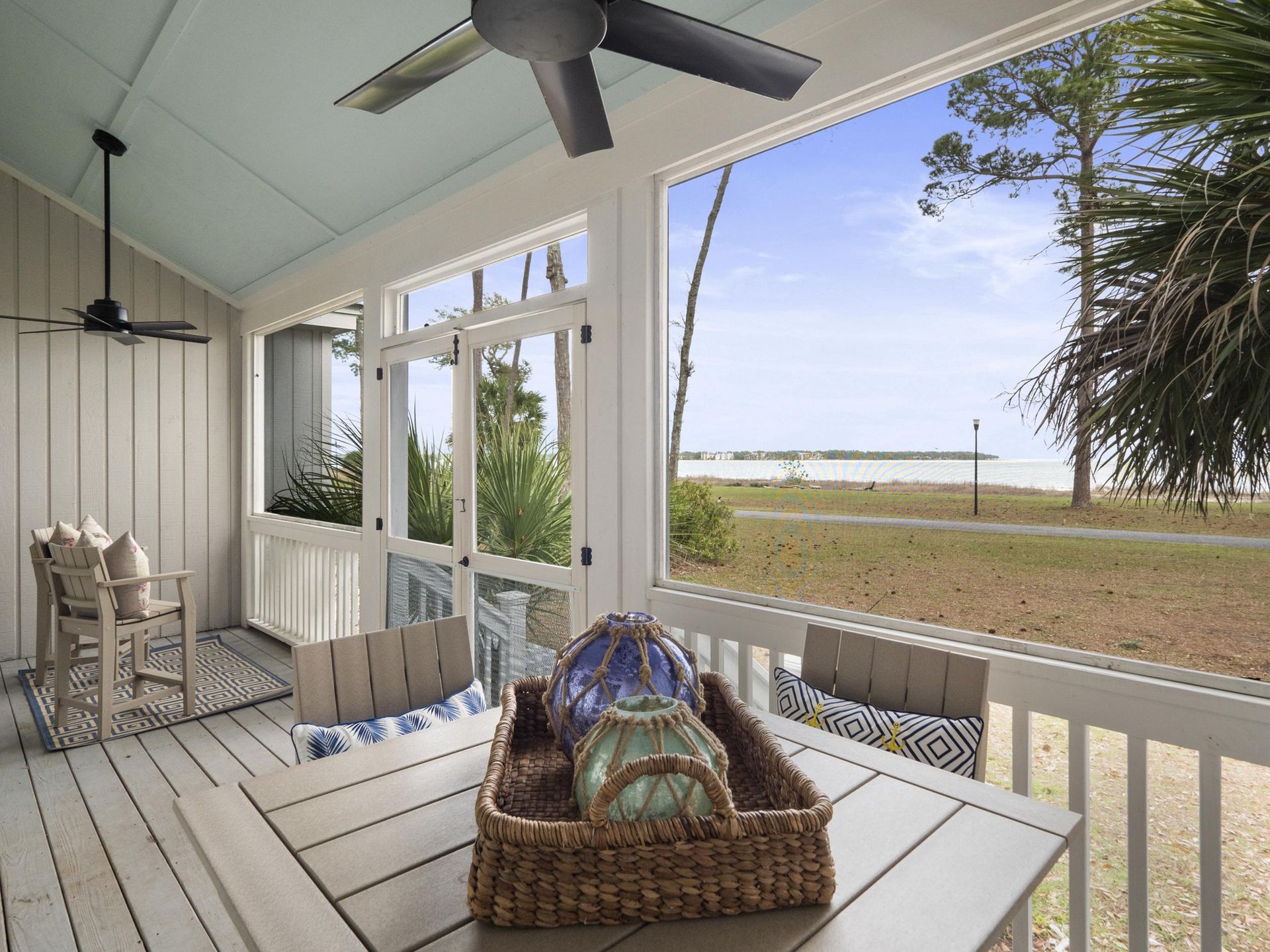 A screened in porch with a table and chairs and a ceiling fan