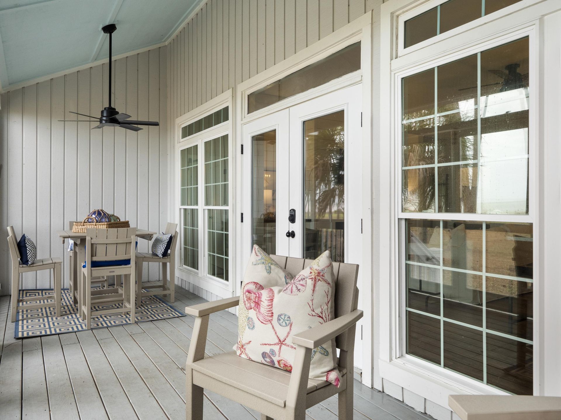 A porch with a table and chairs and a ceiling fan.