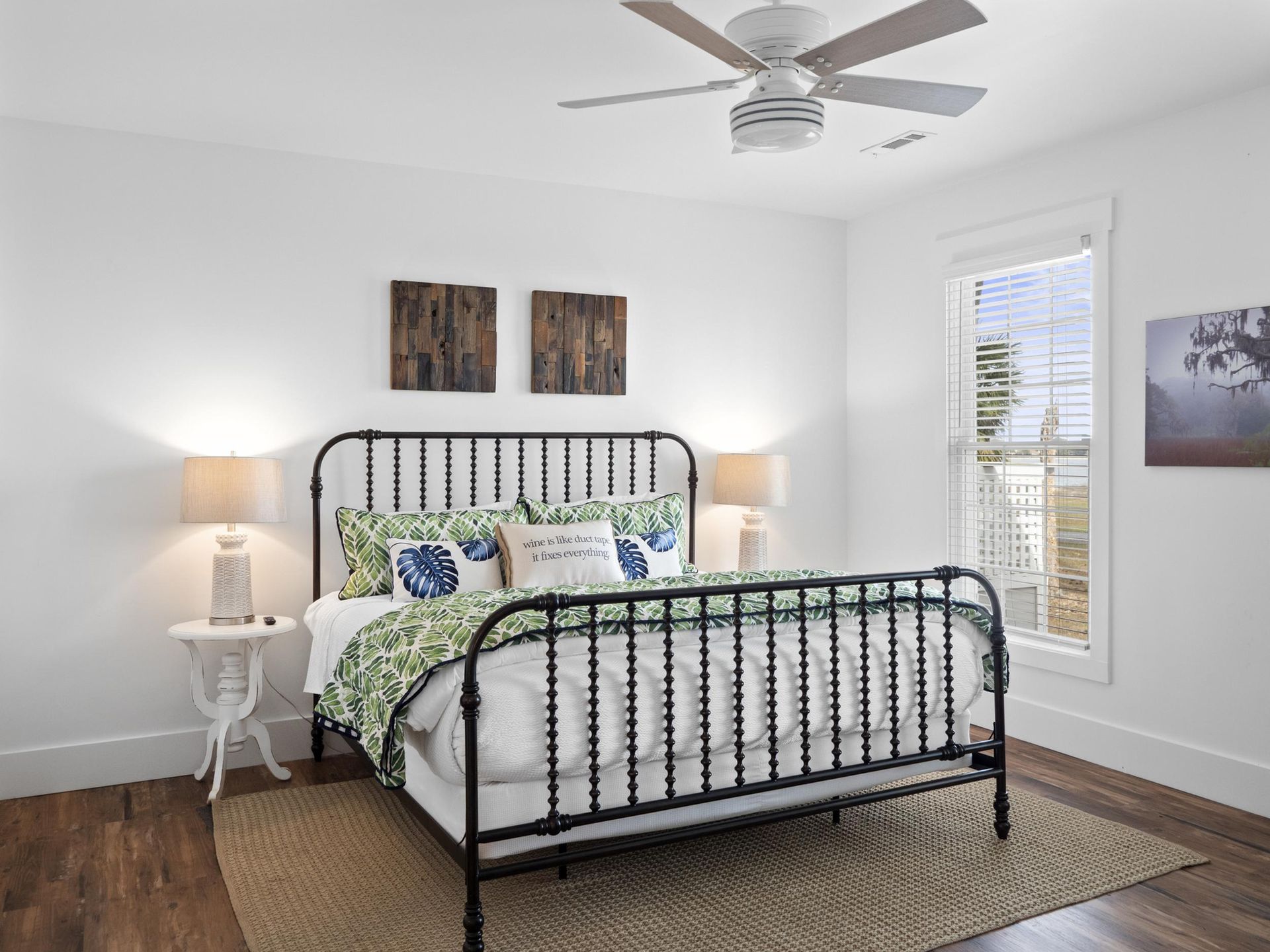 A bedroom with a bed , lamps , and a ceiling fan.