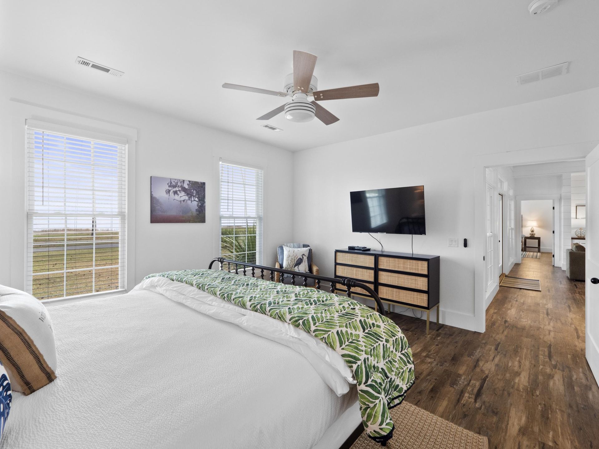 A bedroom with a bed , dresser , television and ceiling fan.