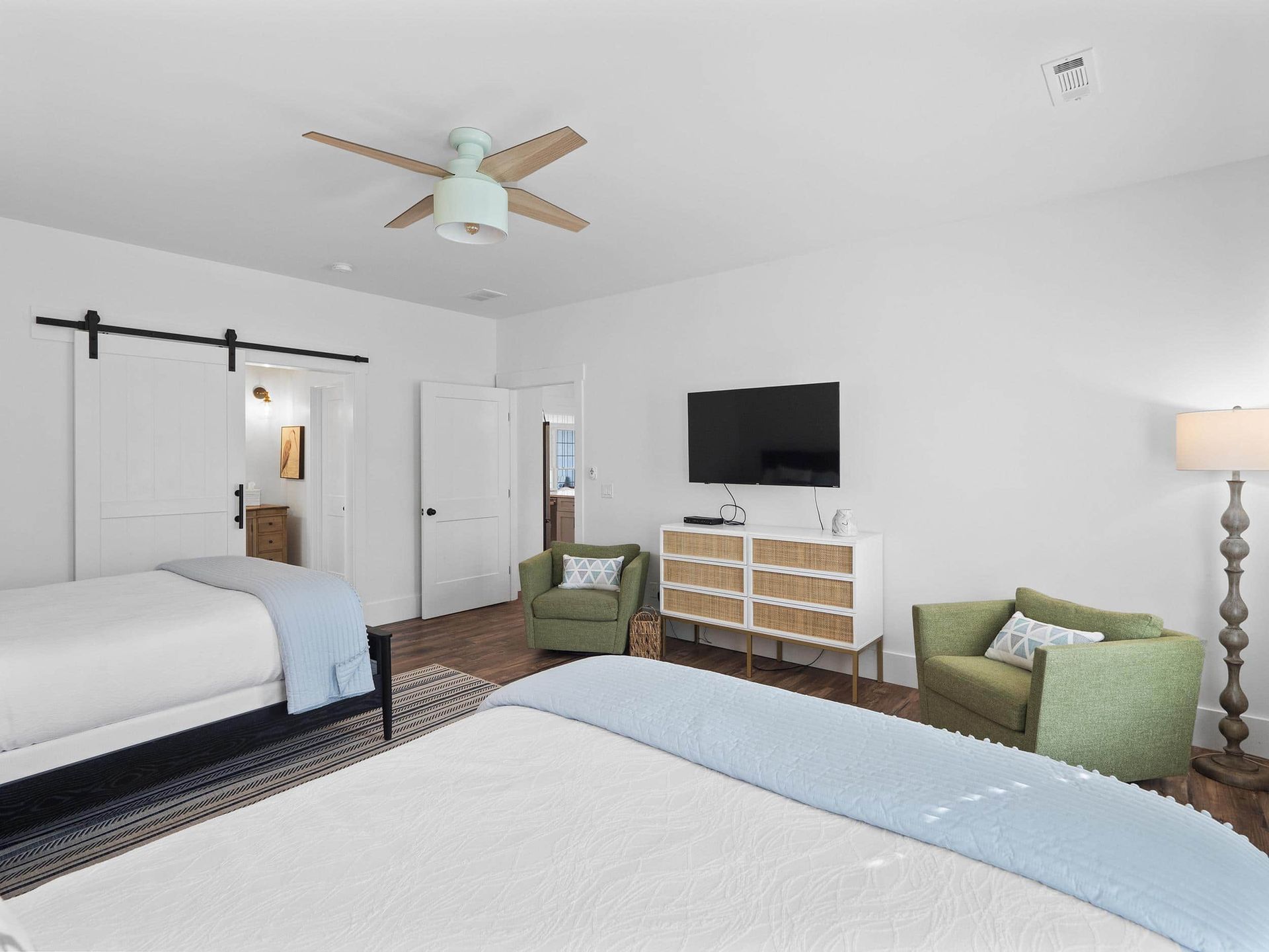 A bedroom with a bed , chair , dresser , television and ceiling fan.