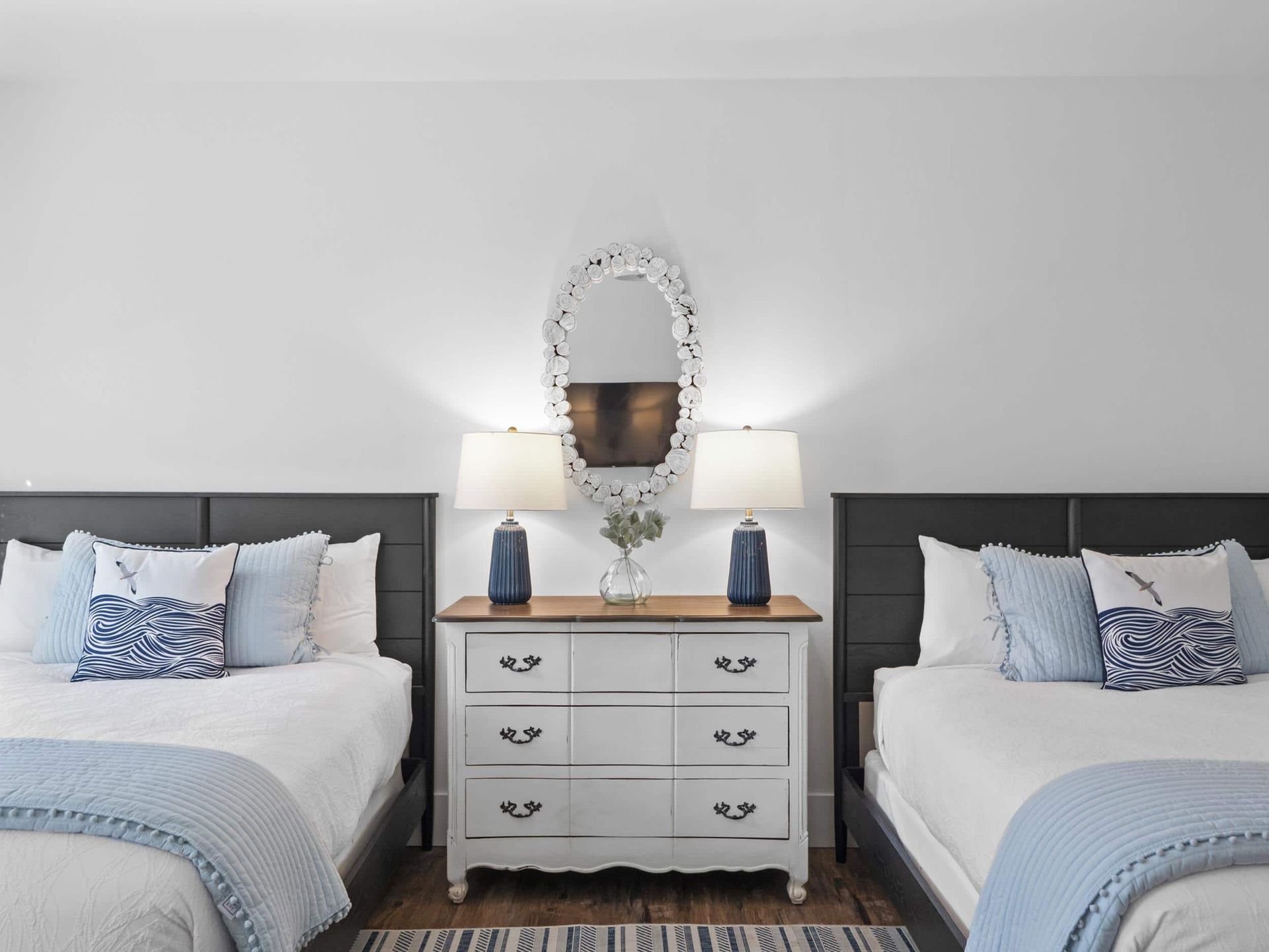 A bedroom with two beds , a dresser and a mirror.