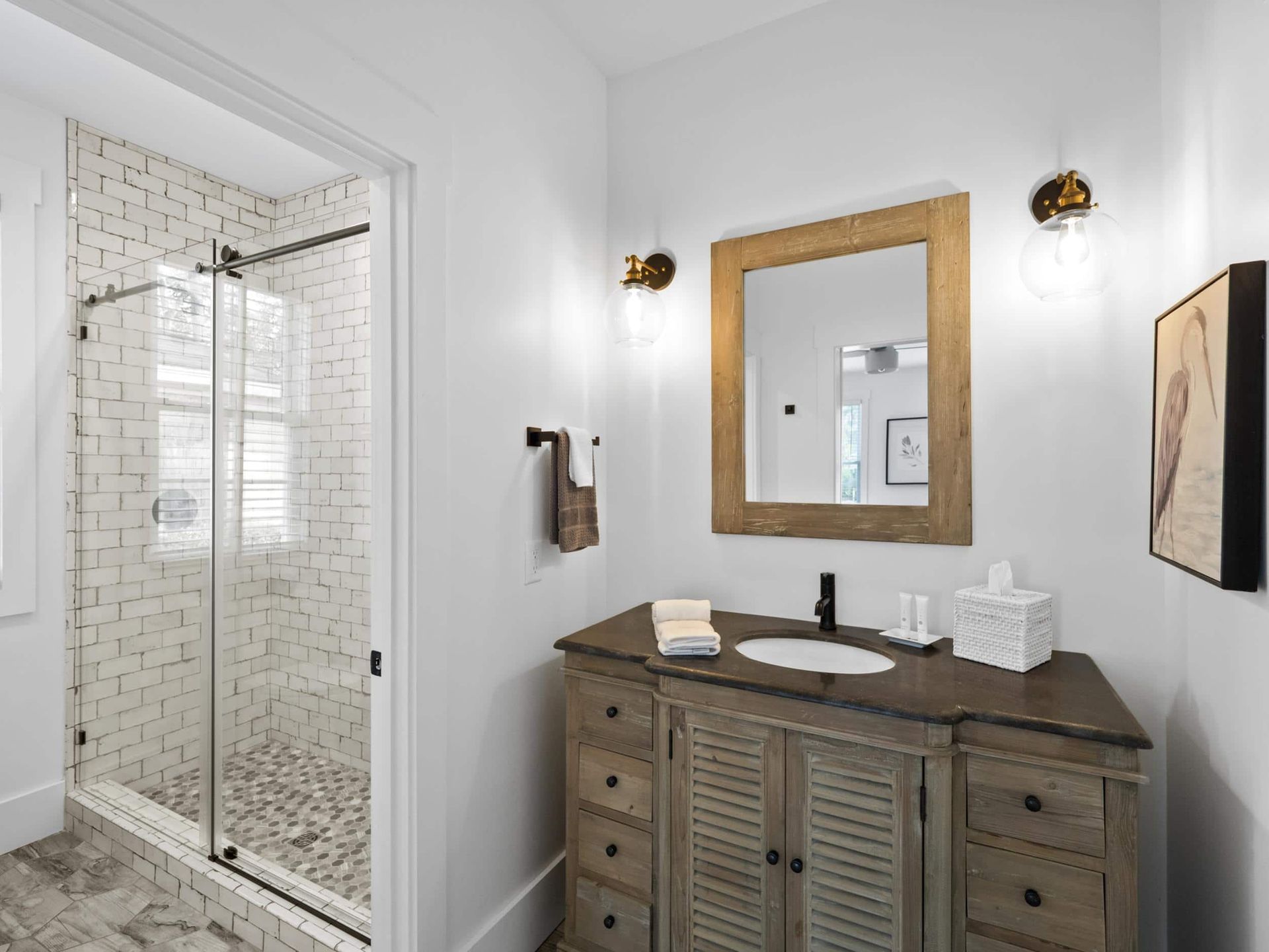 A bathroom with a sink , mirror and walk in shower.