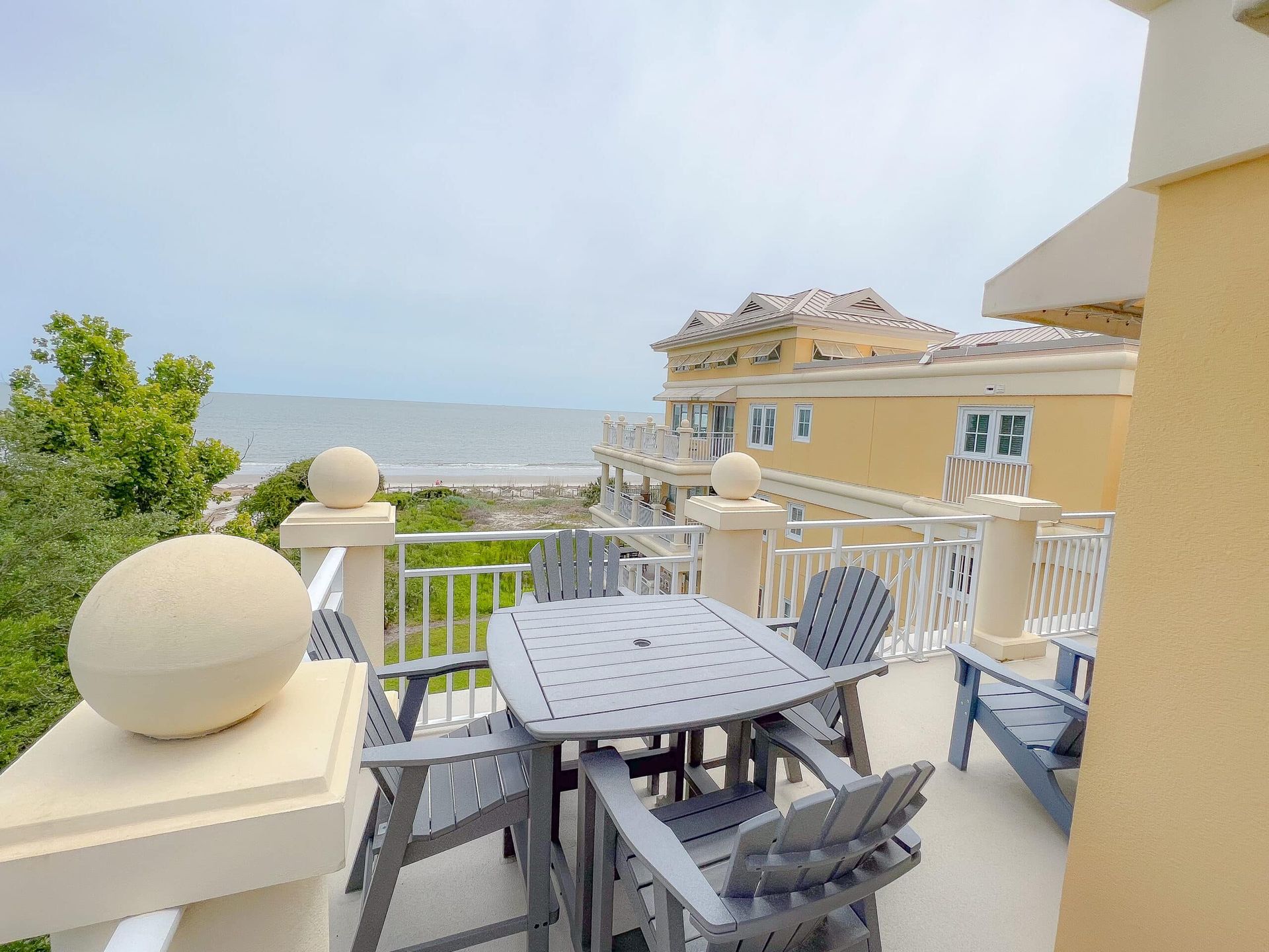 A balcony with a table and chairs overlooking the ocean