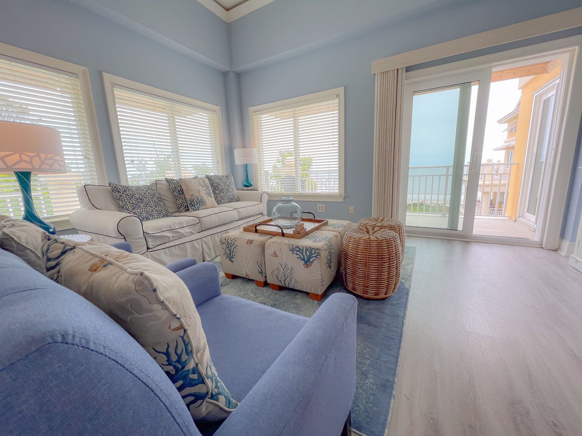 A living room with a couch , chair , coffee table and sliding glass doors.