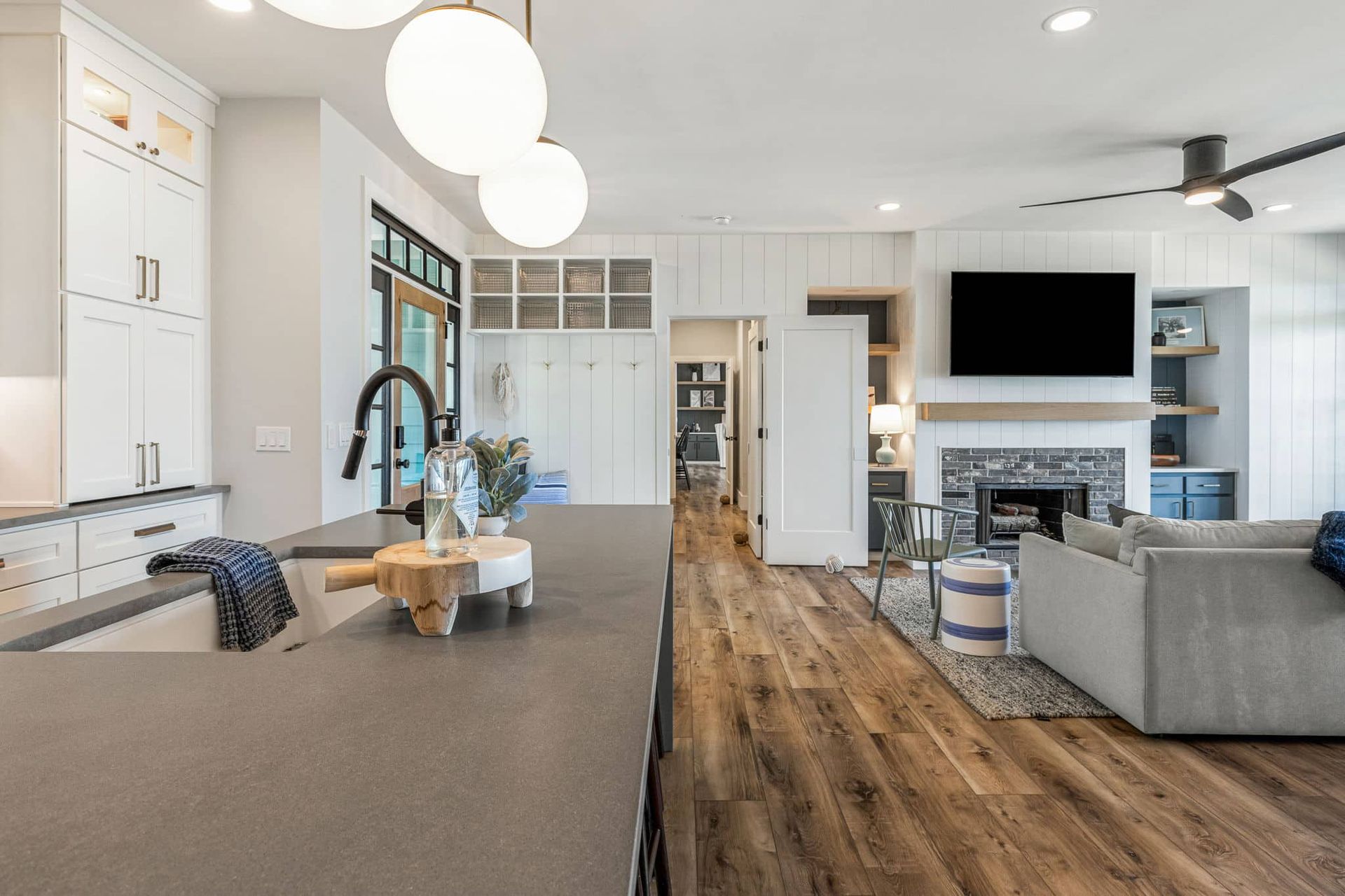 A kitchen and living room in a house with hardwood floors and a flat screen tv.