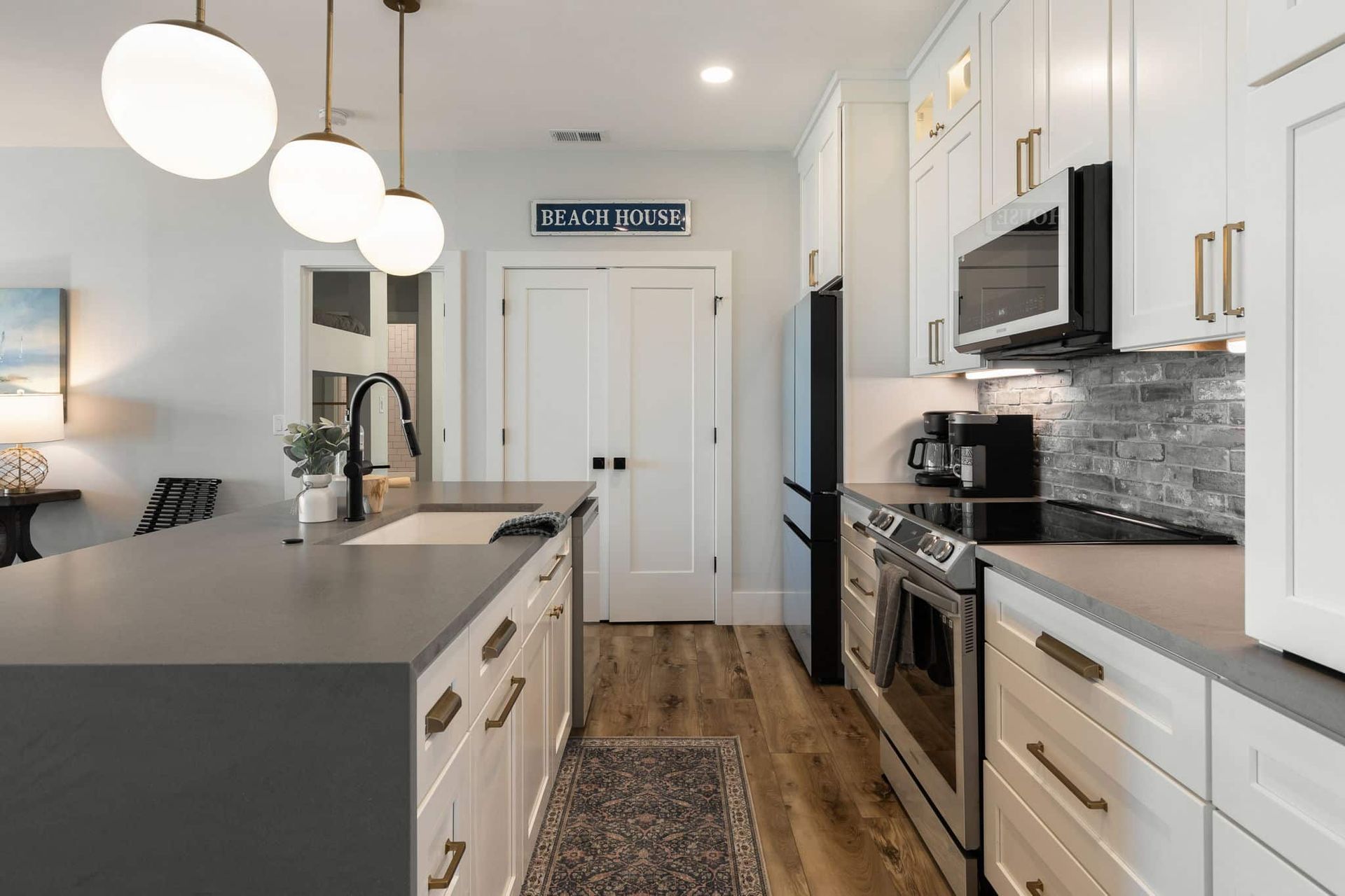 A kitchen with white cabinets , stainless steel appliances , and a large island.