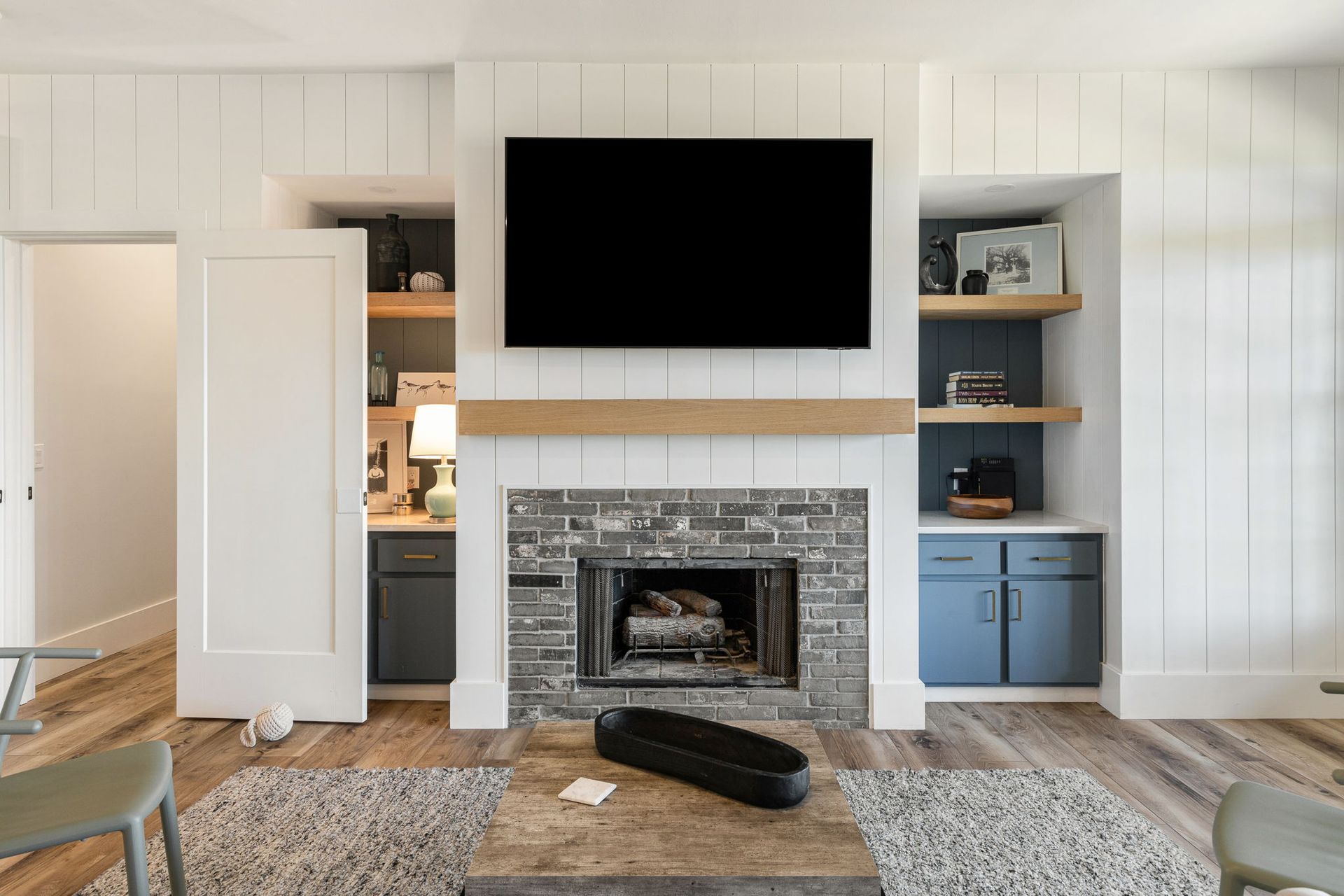 A living room with a fireplace and a flat screen tv on the wall.