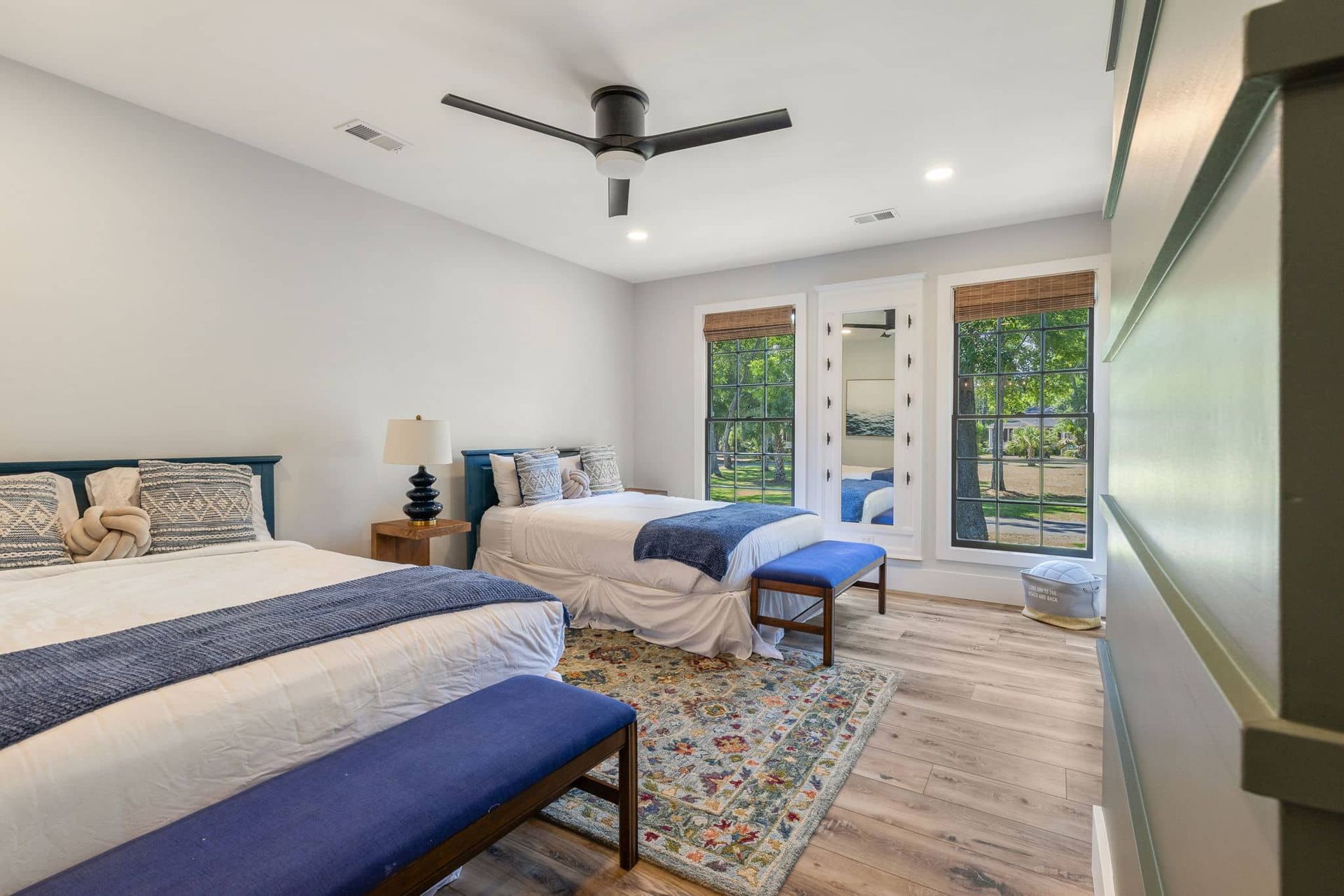 A bedroom with two beds , a bench and a ceiling fan.