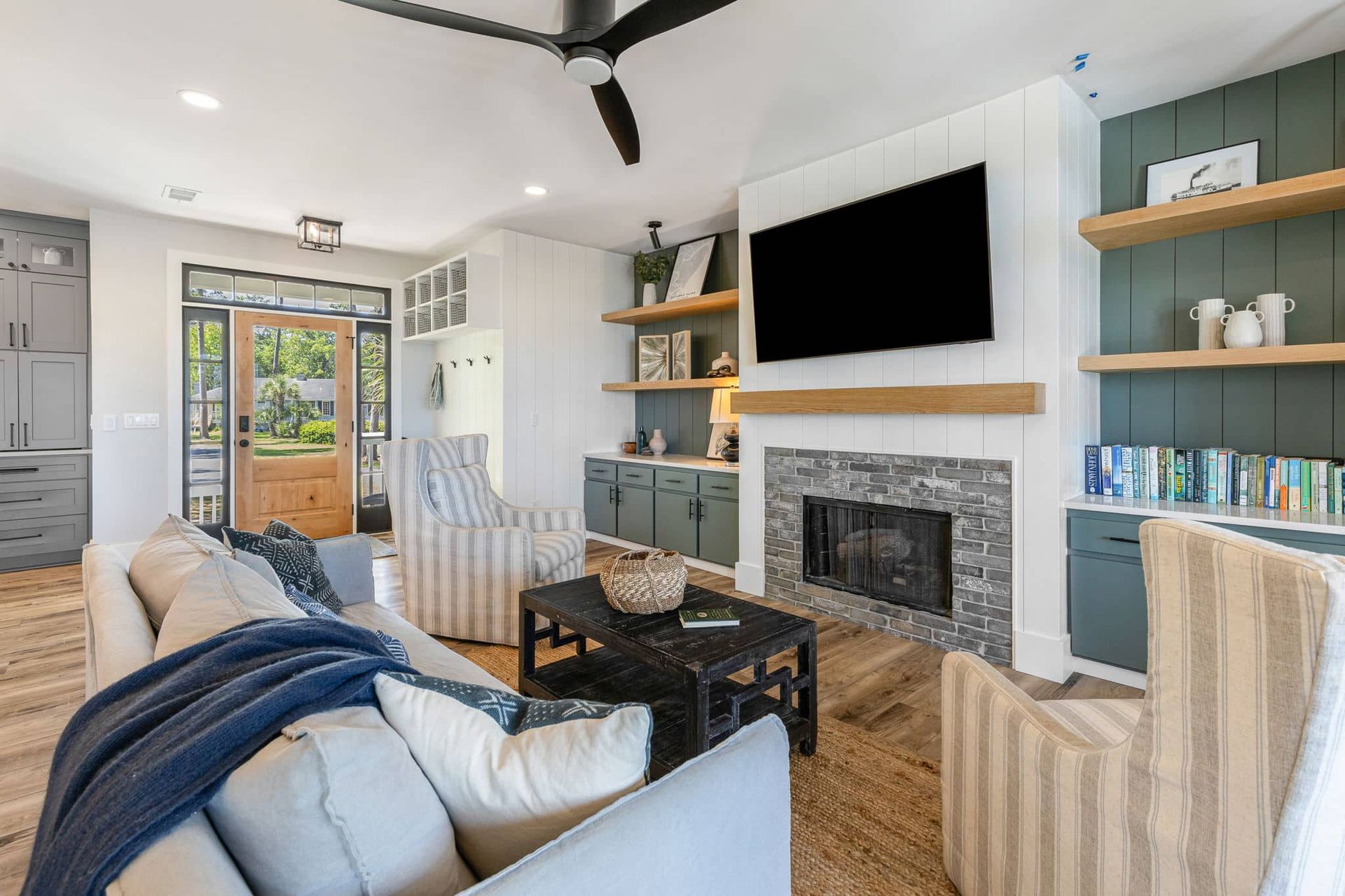 A living room with a couch , chairs , fireplace and television.