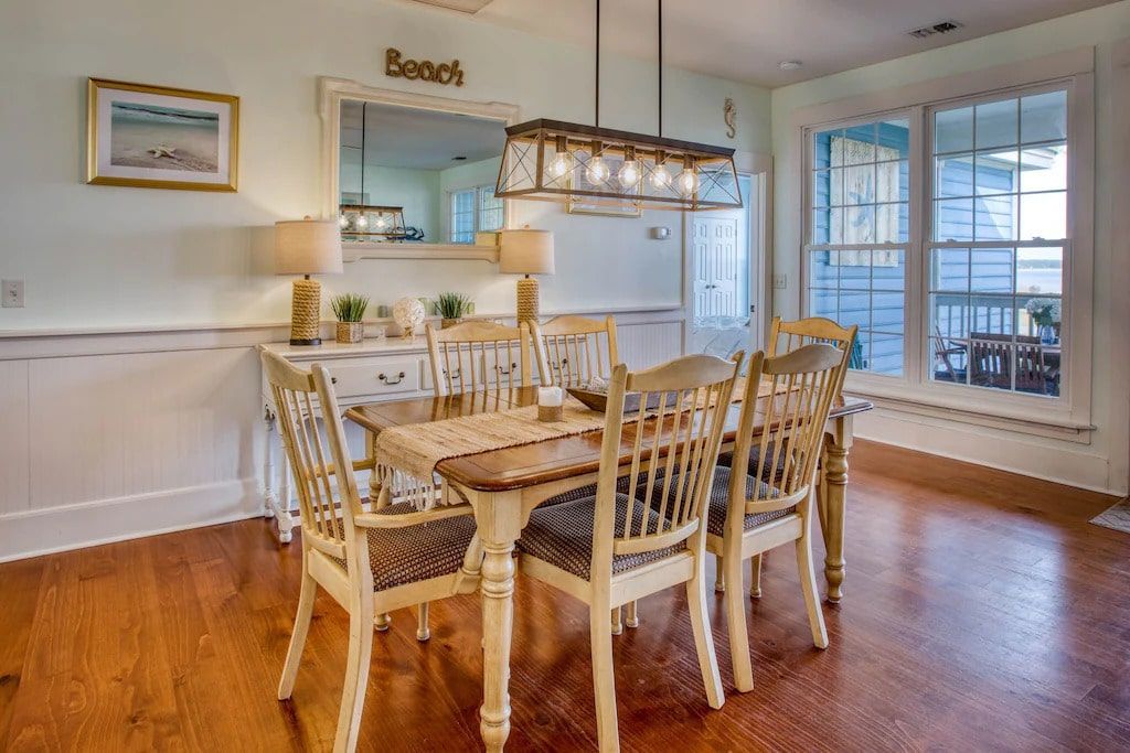 A dining room with a table and chairs and a large window.