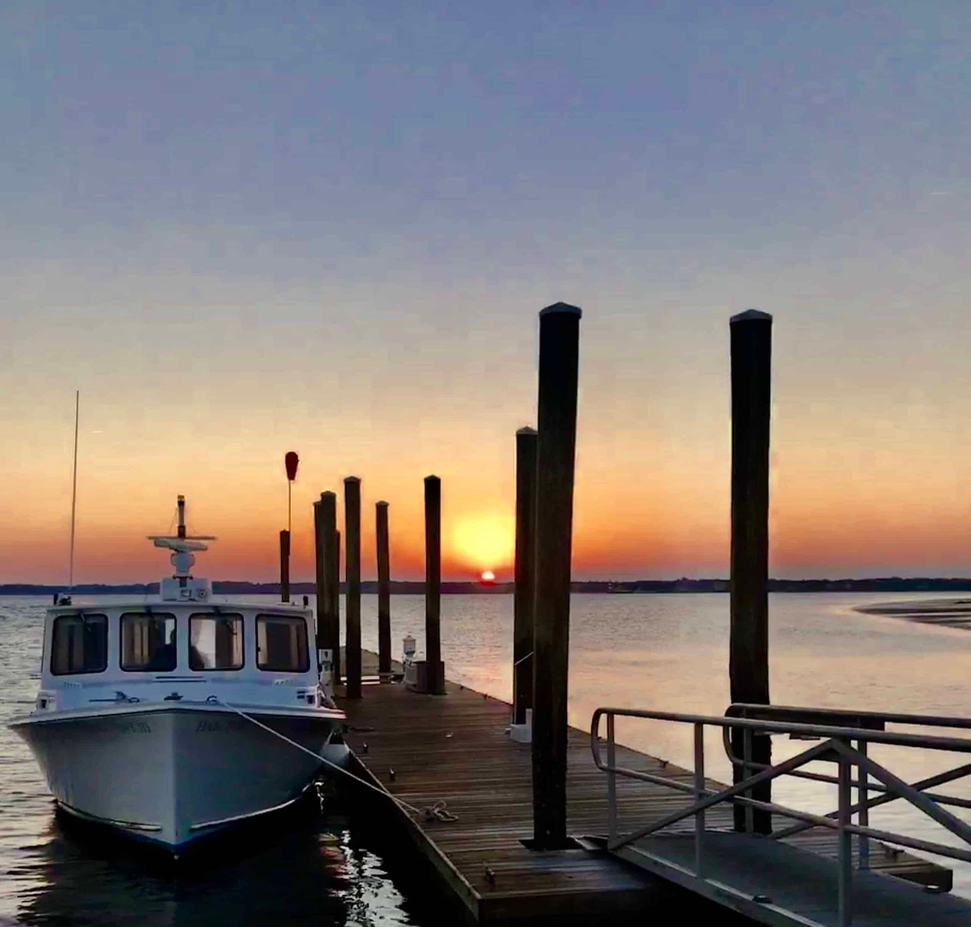 A boat is docked at a dock at sunset