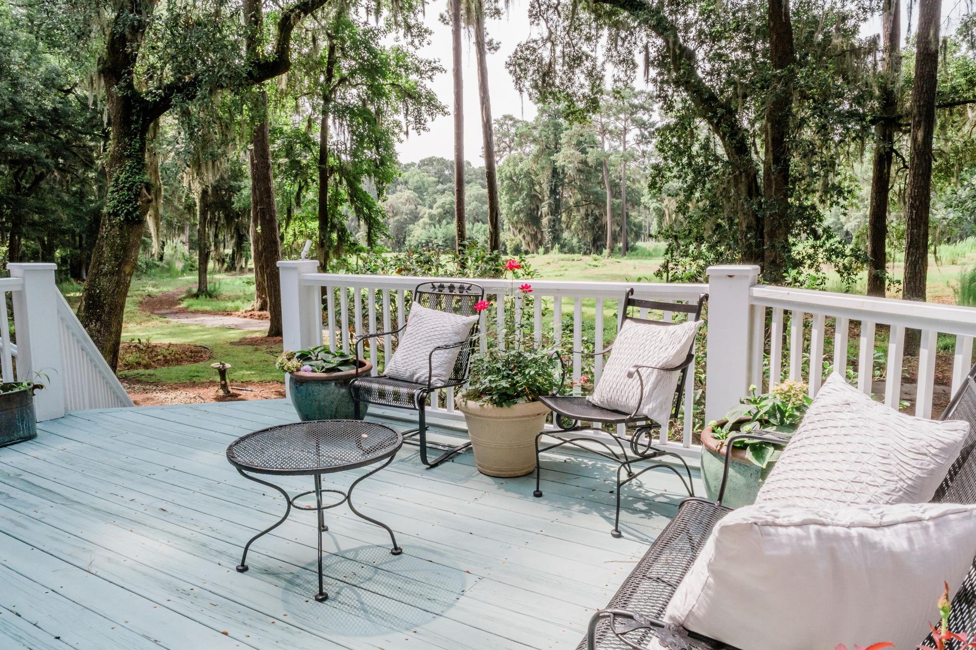 A deck with a table , chairs , and potted plants.