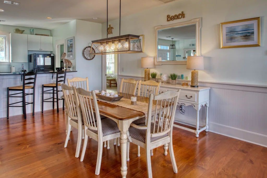 A dining room with a table and chairs and a mirror.