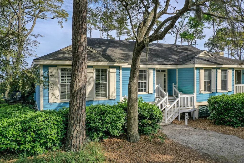 A blue house with white shutters and a tree in front of it.