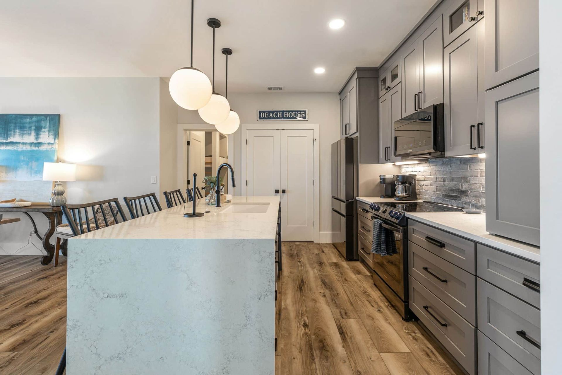 A kitchen with gray cabinets , stainless steel appliances , and a large island.
