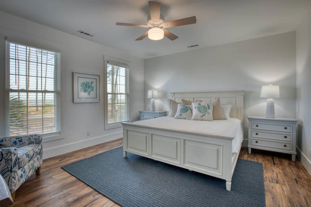 A bedroom with a king size bed , two nightstands , a chair , and a ceiling fan.