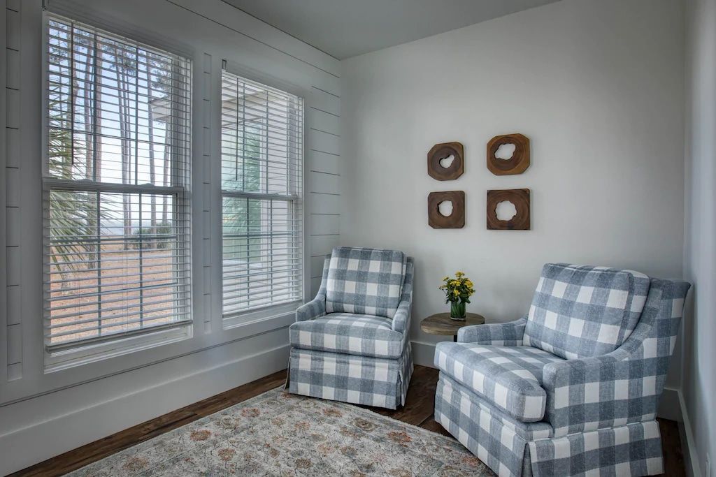 A living room with two chairs and two windows.