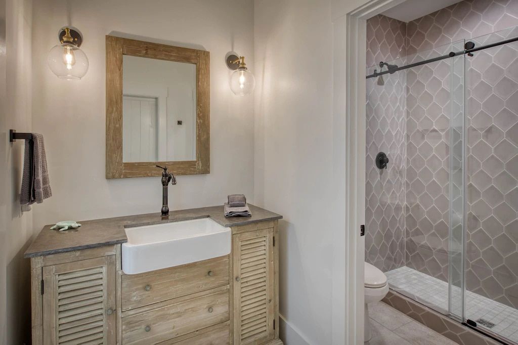 A bathroom with a sink , mirror and shower.