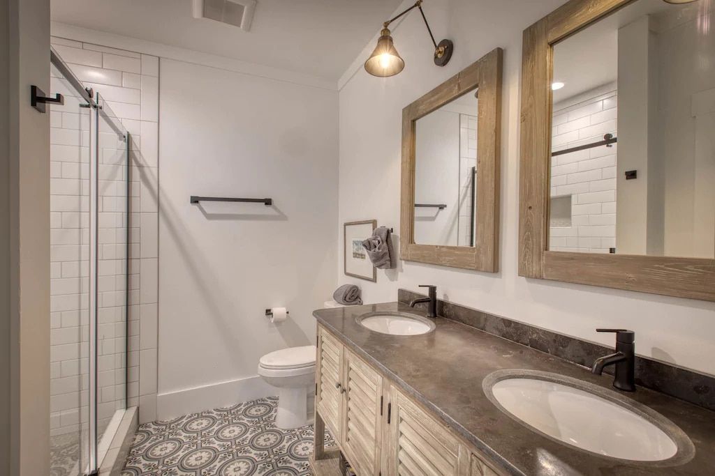 A bathroom with two sinks , a toilet , and a shower.